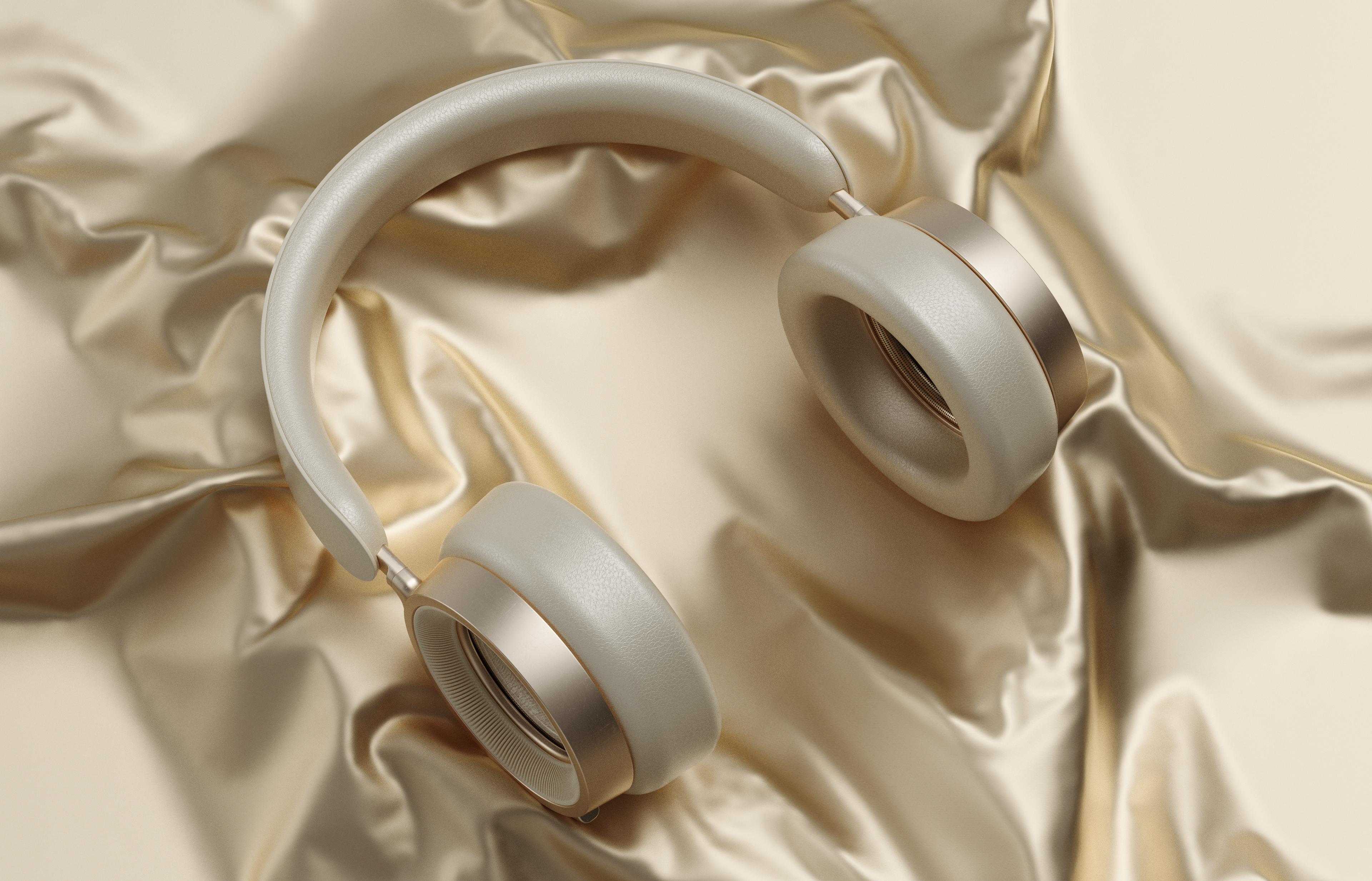 Stylish beige and gold over-ear headphones displayed on luxurious, crinkled gold fabric.