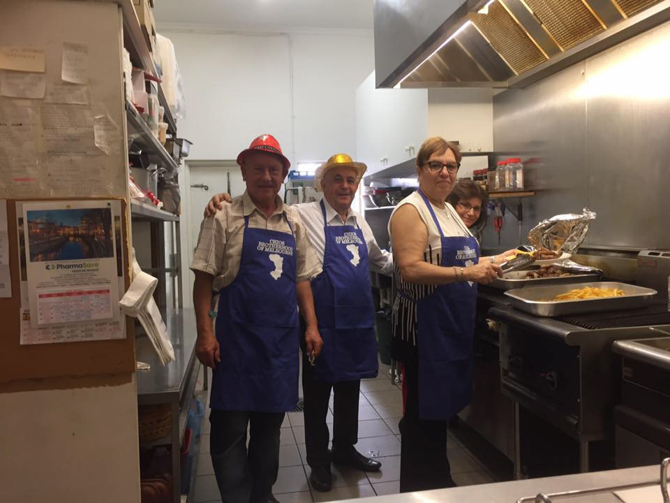 Kitchen Team of the Chios Brotherhood of Melbourne Proudly Donning Their Custom-Designed Aprons During Culinary Preparations