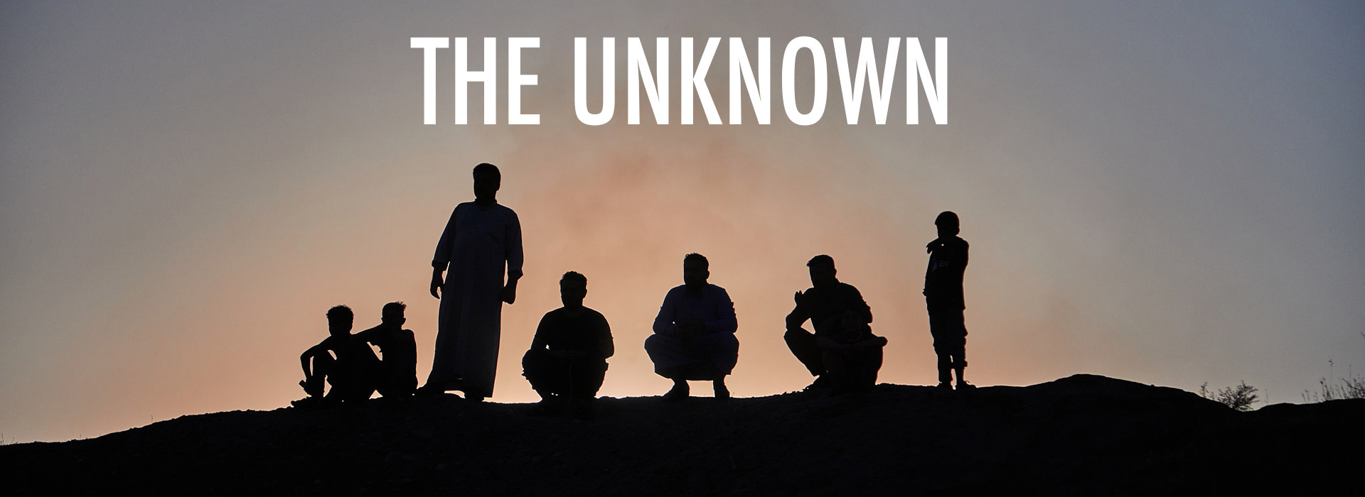 Silhouettes of men gathered on a hilltop at dusk, title image of the documentary The Unknown, about mental health in conflict and post-war countries