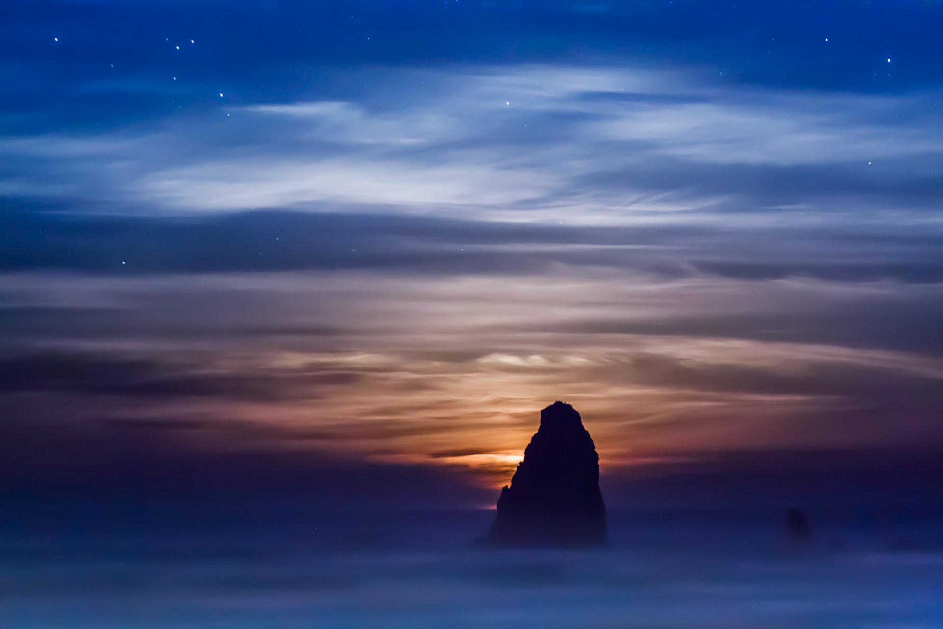seascape taken at dawn as the moon sets behind a seastack at Cannon Beach, Oregon