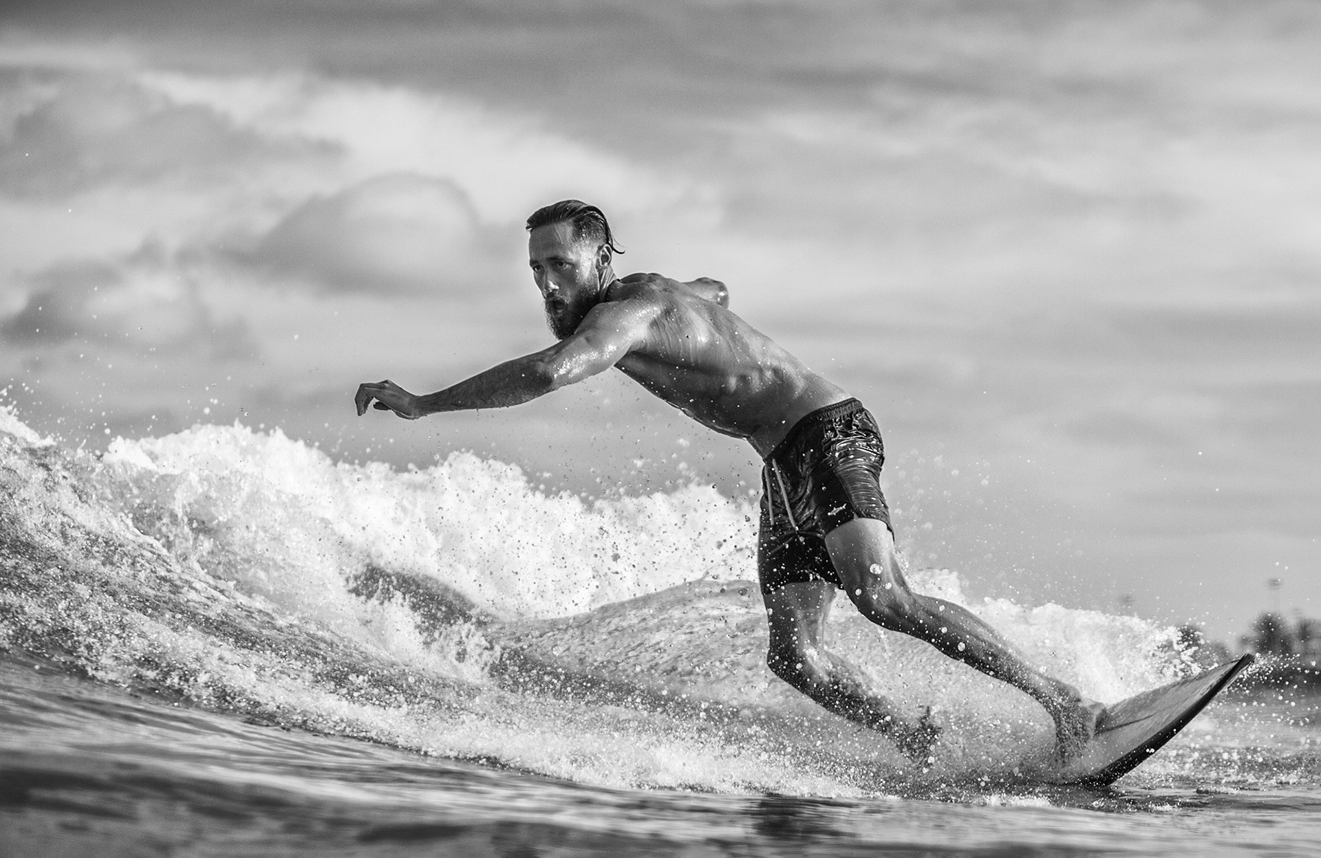 Fotografía en blanco y negro de un surfista surfeando una ola y girando