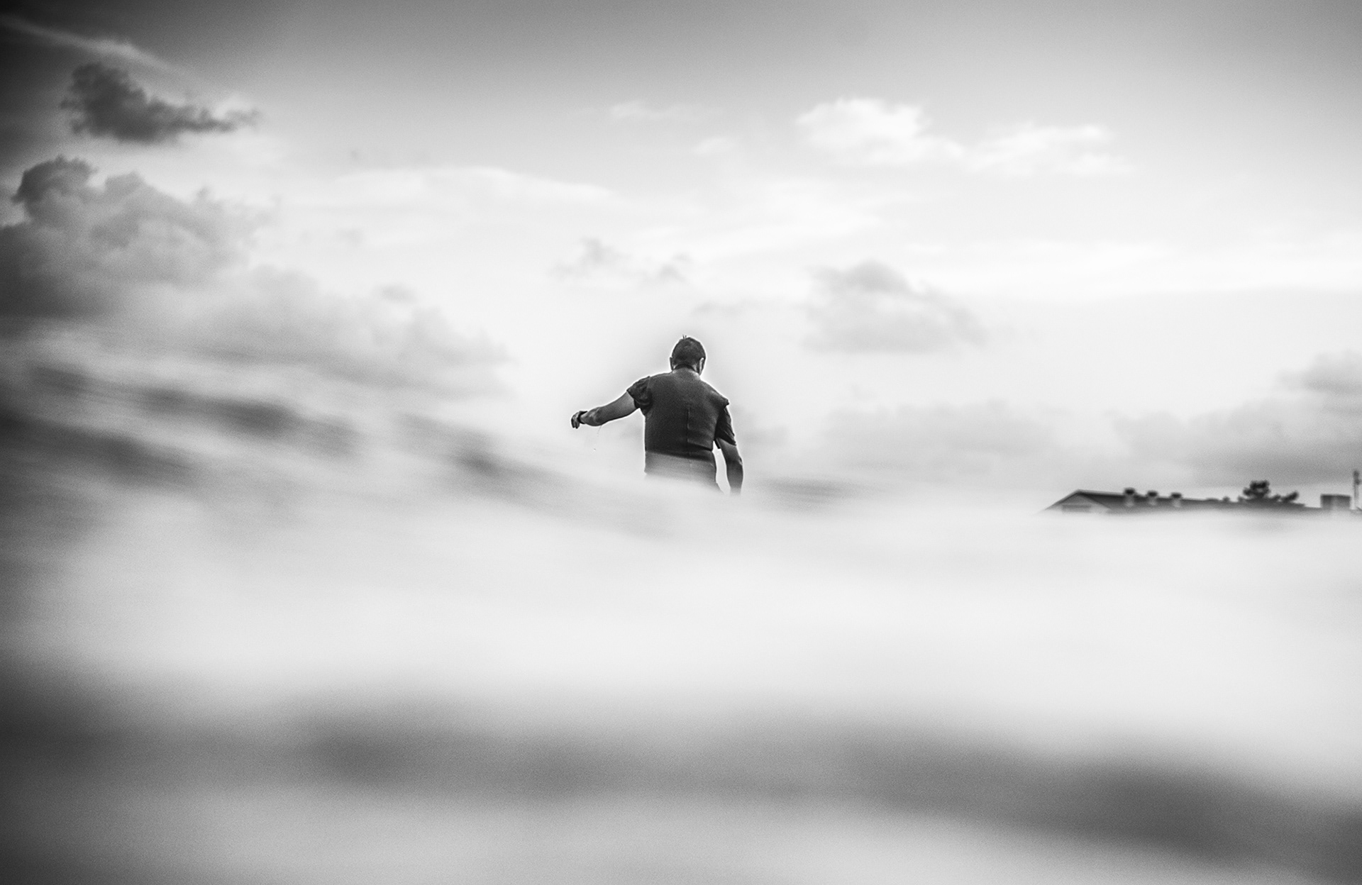 Fotografía en blanco y negro de un surfista de espaldas surfeando una ola