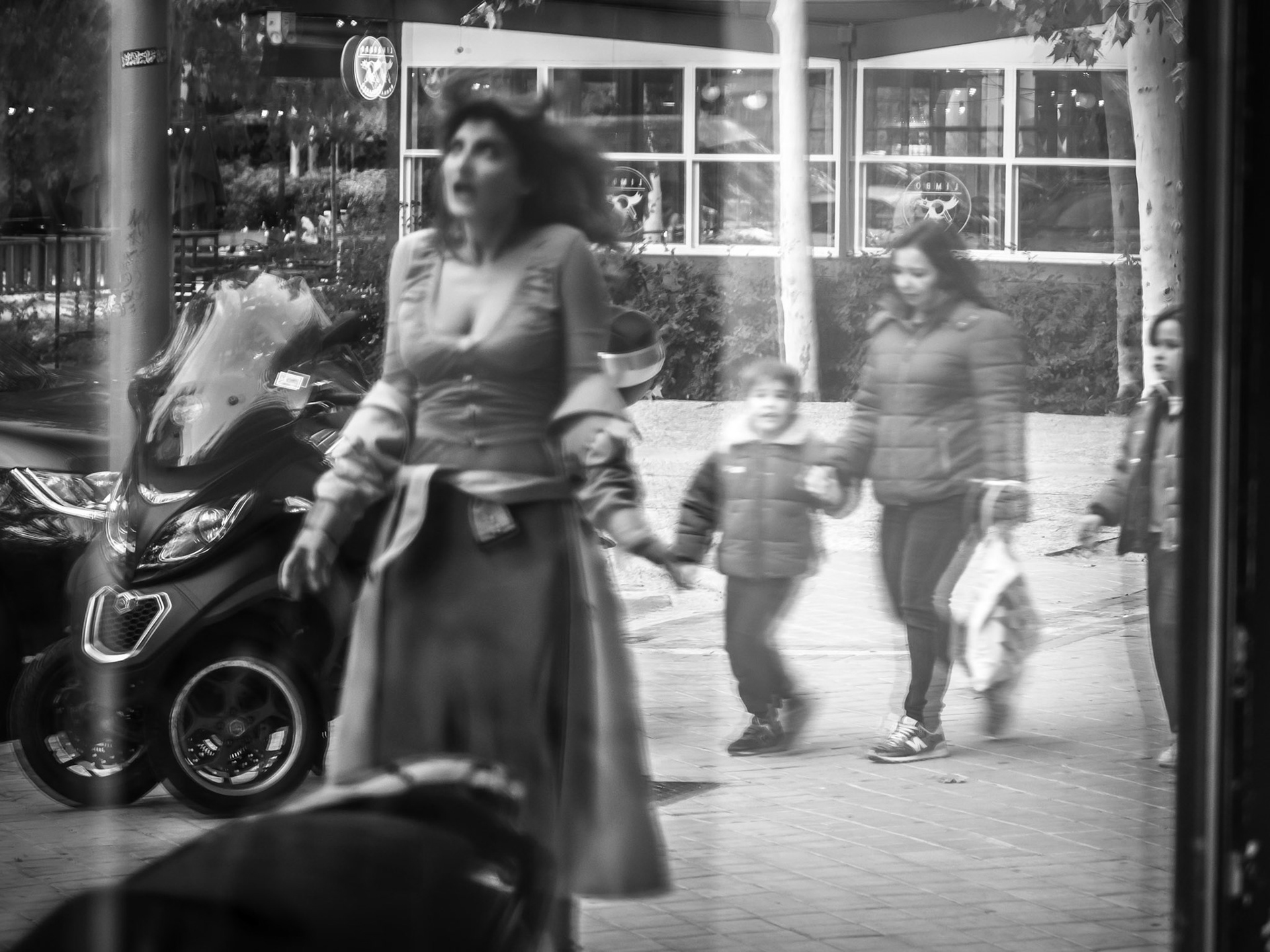 A woman stands still in fragmented reflection, her hair forming devilish horns — an accidental crown of both mischief and insight. She is captured mid-transformation, caught in a moment of inner reckoning, teetering between darkness and light. A child gazes in silent awe, witnessing an ephemeral, otherworldly figure, as if glimpsing the embodiment of a profound truth beyond his understanding.