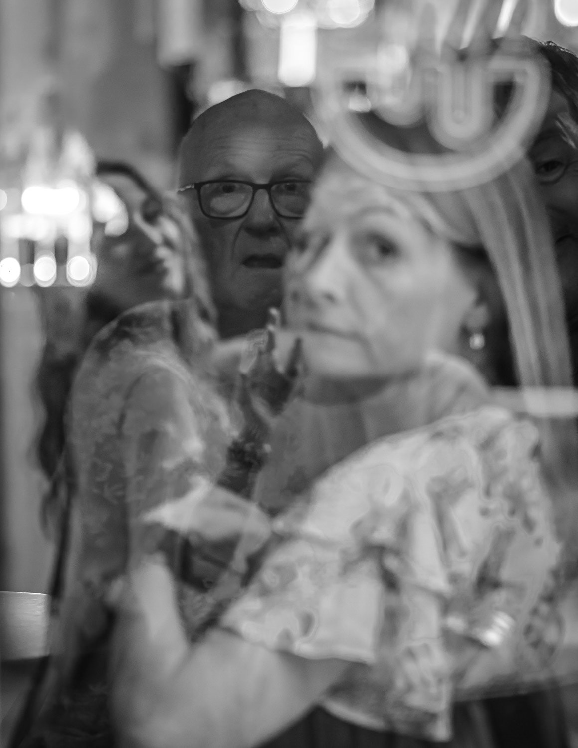 Two friends appear to be in a playful scuffle through a café window. The reflection blurs the line between affection and conflict, creating a metaphor for human relationships — layered and complex.