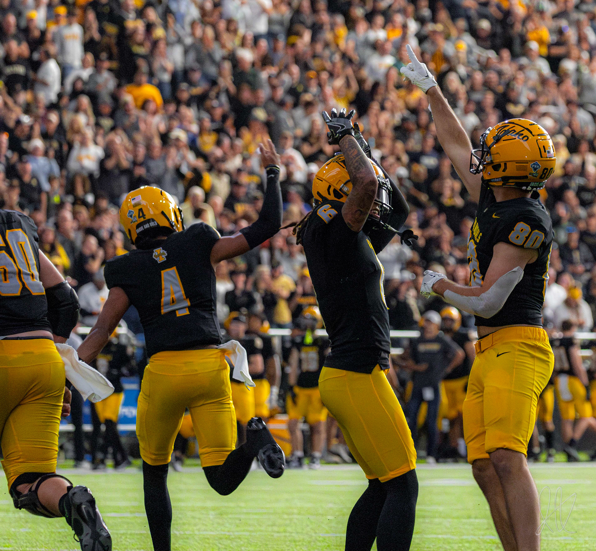 Hayden Hatten and teammates celebrate after a touchdown, surrounded by a hyped up crowd