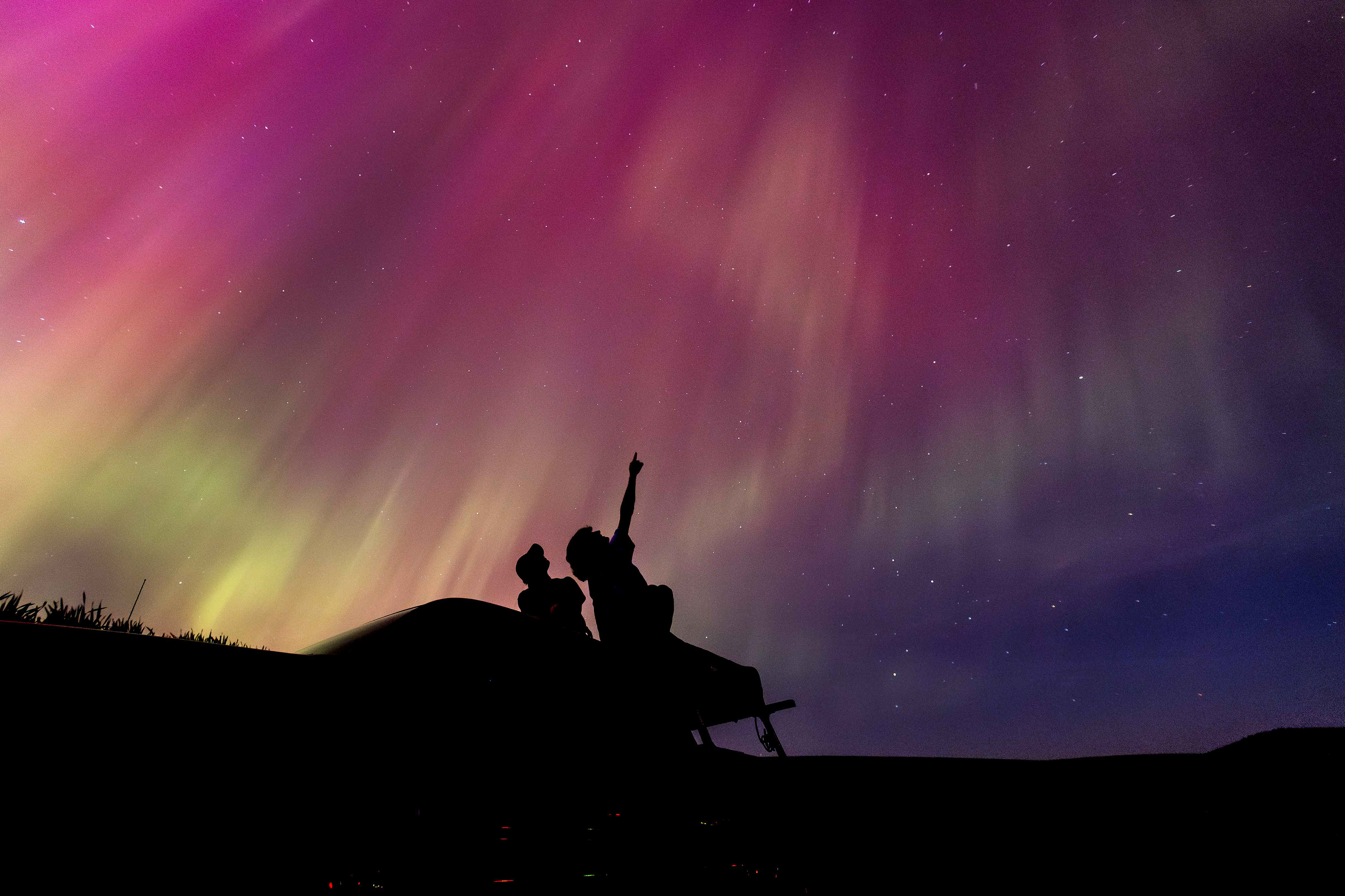 Peter Voller and Ian Kolaja sit atop a truck to watch the northern lights in Moscow, Idaho on May 10, 2024. (Photo/John Keegan)