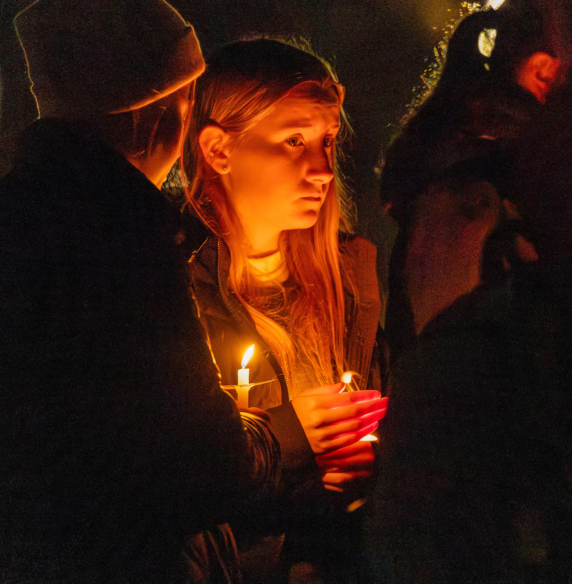An attendee of the candlelight vigil for the four murdered University of Idaho students warming their hands with the flame of their candle, Nov. 13, 2023. (Argonaut/John Keegan)
