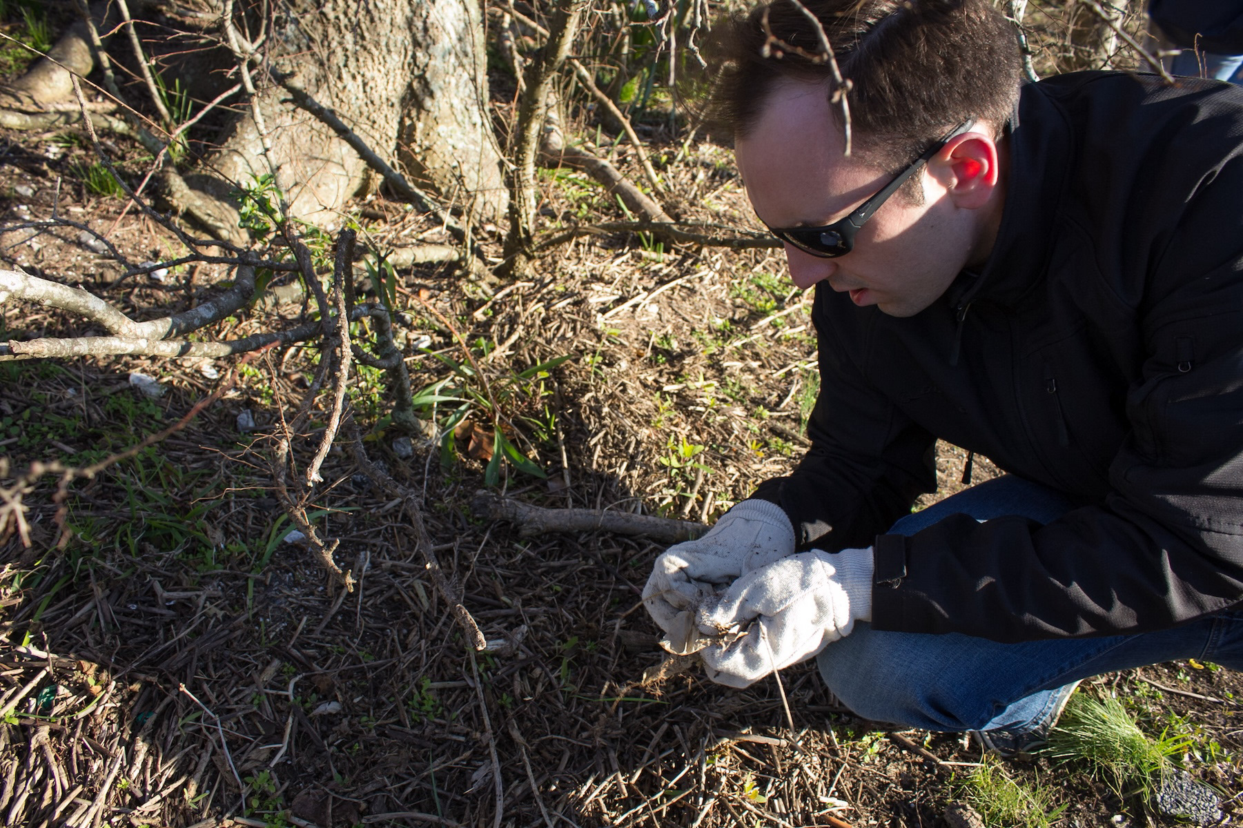 A volunteer collecting litter from a Charleston marsh during a company partnership event