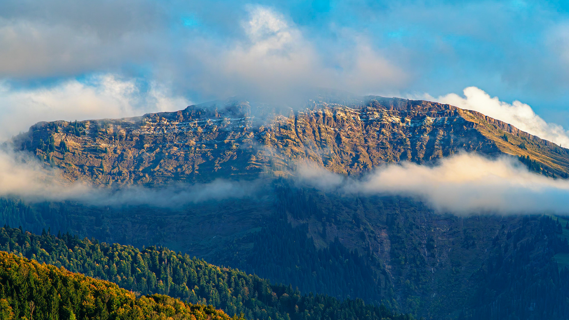 Ein majestätischer Berggipfel erhebt sich inmitten einer malerischen Landschaft im Allgäu. Zarte Wolken umhüllen den Gipfel und verleihen dem Bild eine mystische Atmosphäre. Die Farben sind warm und einladend, und die Perspektive bietet einen atemberaubenden Blick auf die umliegende Natur.