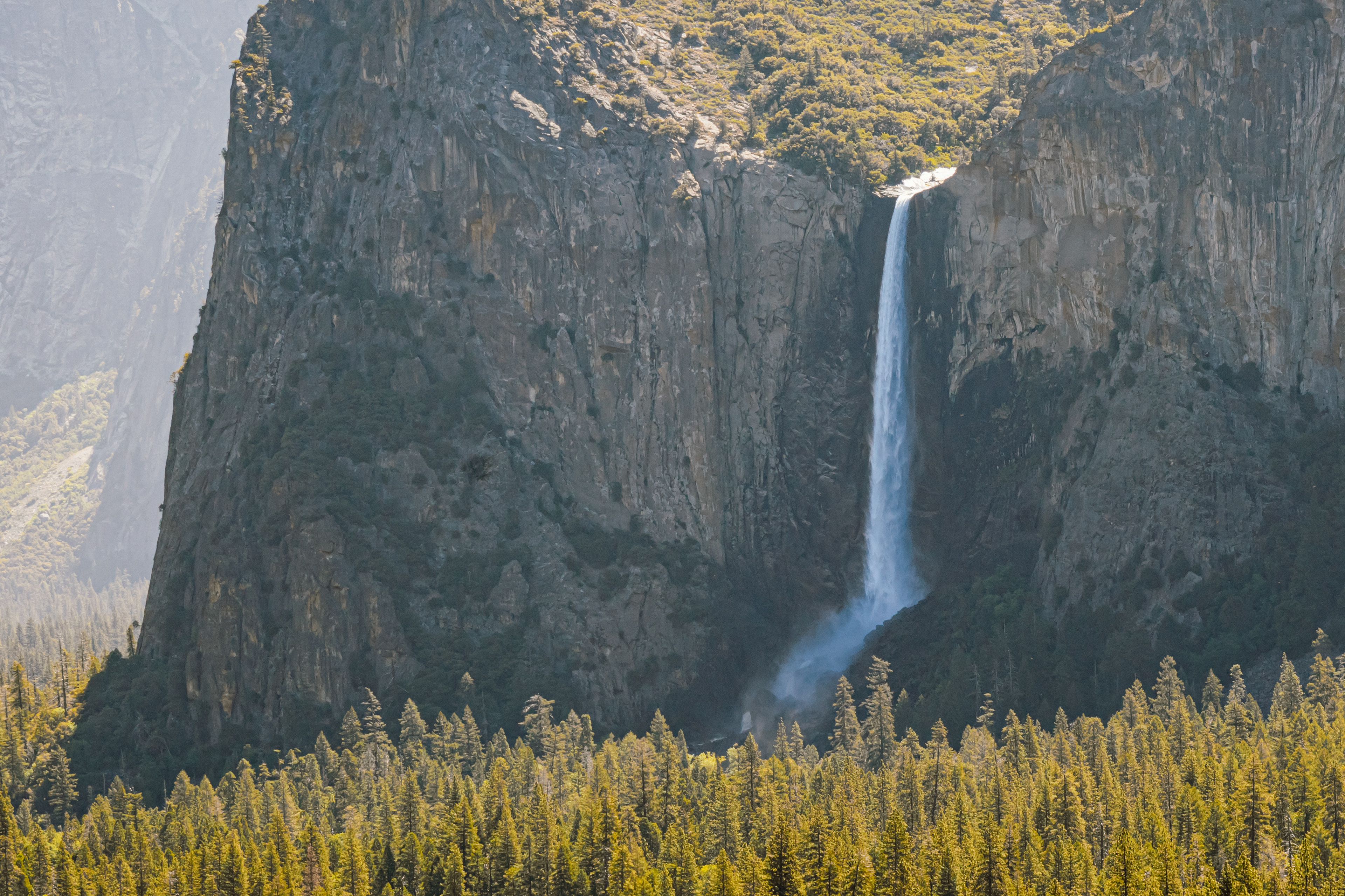 That powerful waterfall gushes down a rocky cliff, surrounded by a vibrant green forest. It really makes you feel the force of nature.