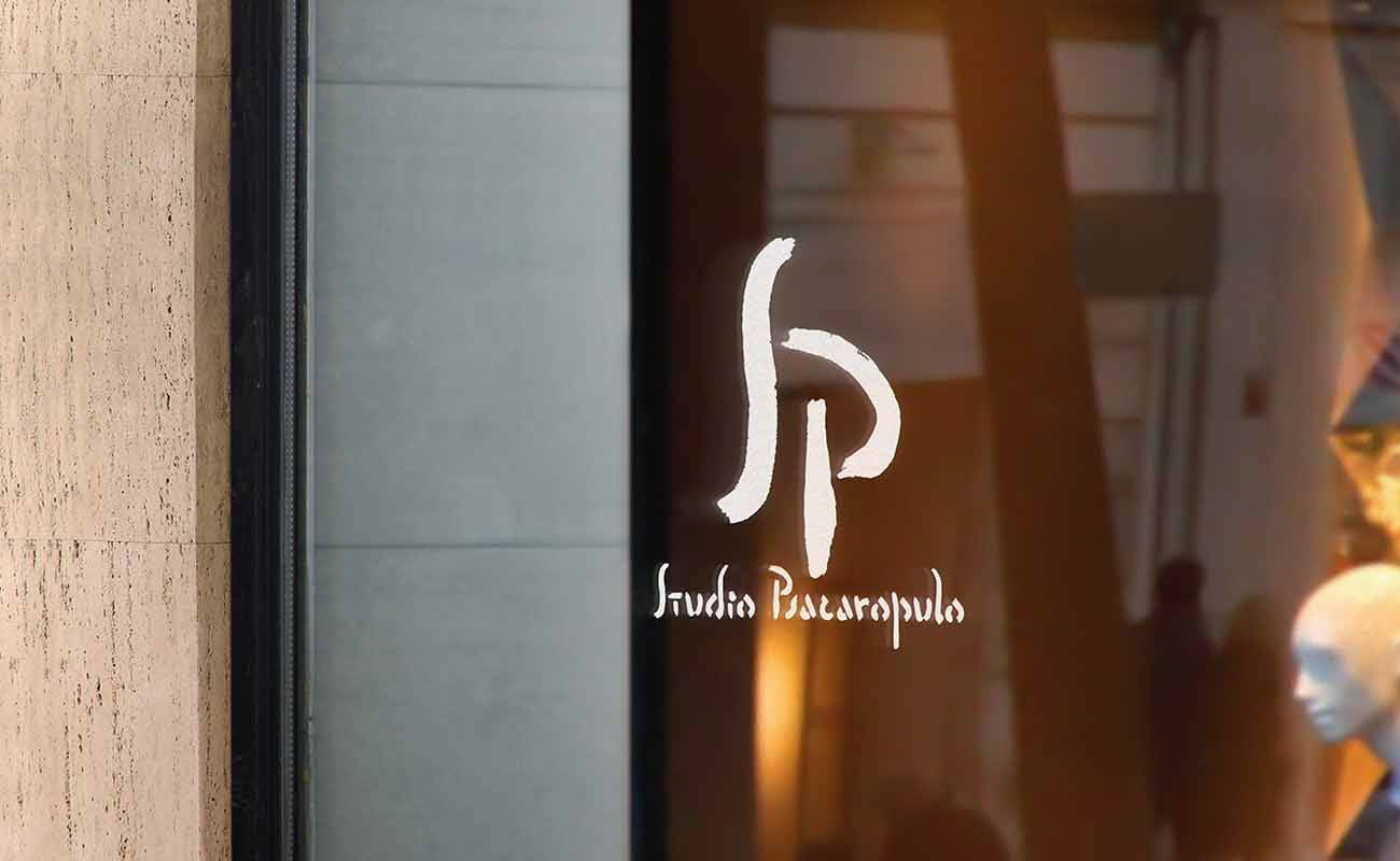 Studio Psacaropulo logo designed by graphic designer Darka White, displayed on a glass window, reflecting the artistic heritage of the association.