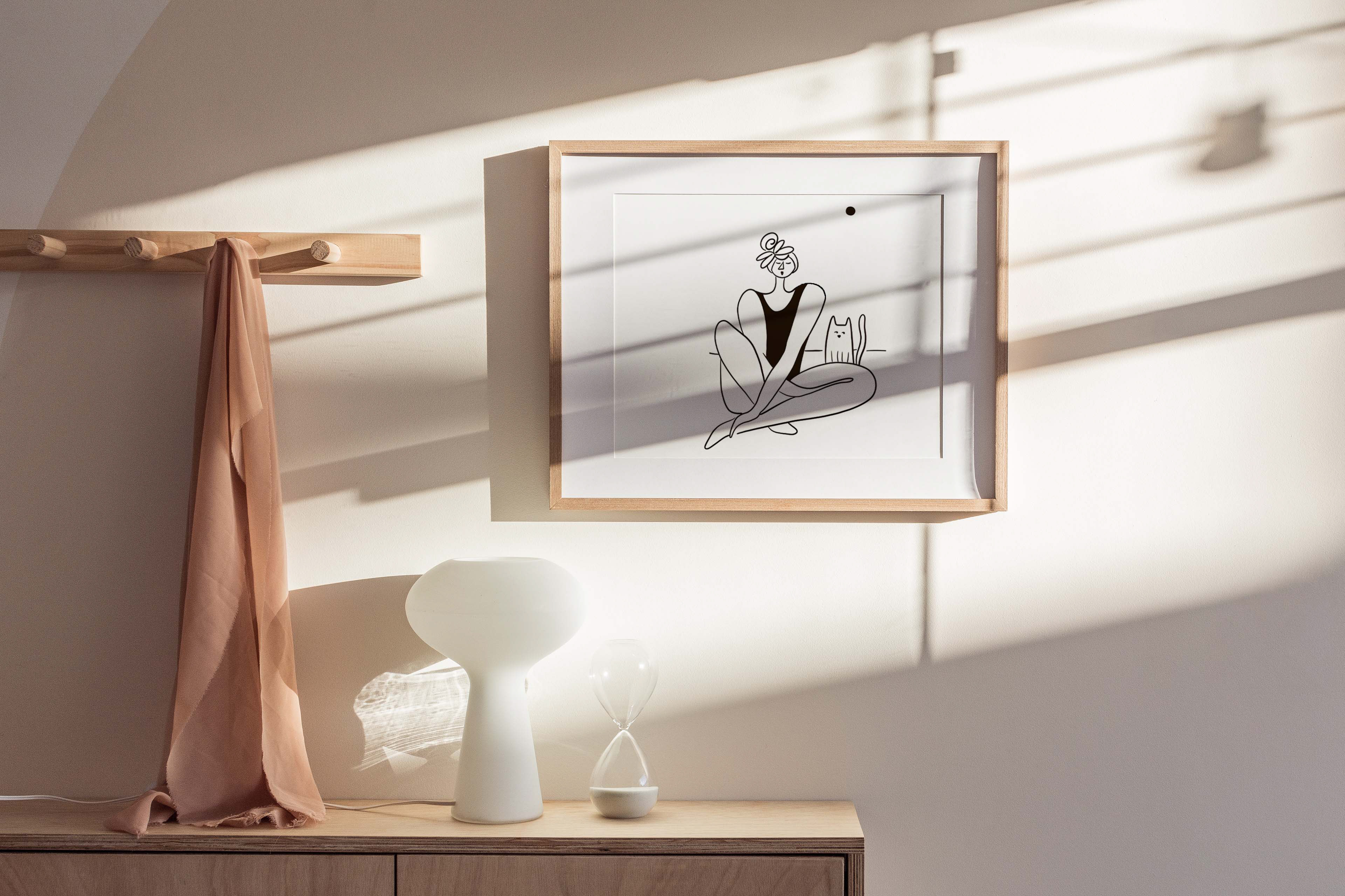 Modern black and white illustration of a woman sitting with a cat, displayed in a wooden frame, adding elegance to any interior space. Illustration by Darka White Krizman.