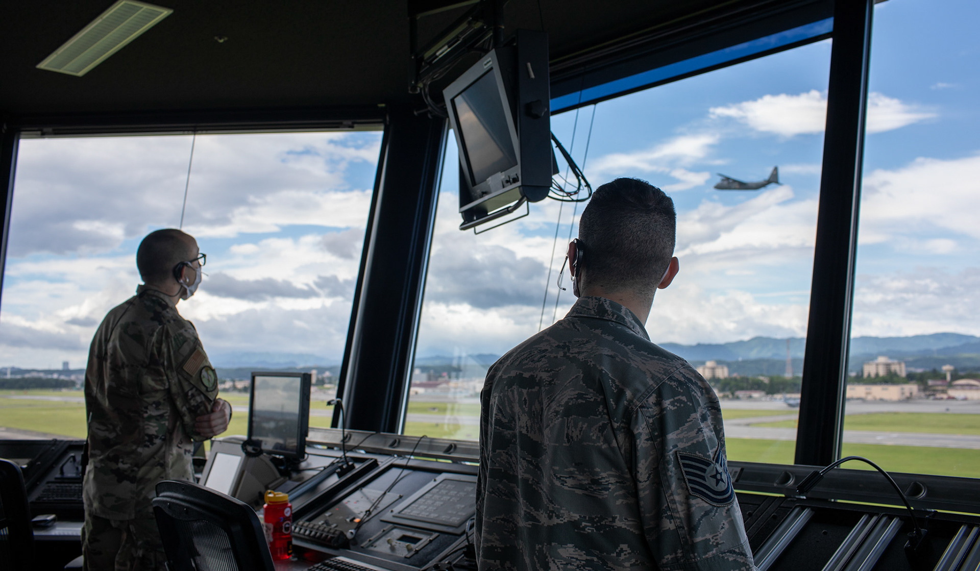 (Right to left) Tech. Sgt. Gregory Nitch and Staff Sgt. Grant Krause, both with the 374th Operations Support Squadron air traffic controllers, observe a C-130J Super Hercules takeoff at Yokota Air Base, Japan, June 11, 2020. Responsible for managing the flow of aircraft through all aspects of their flight, ATC specialists ensure the safety and efficiency of air traffic on the ground and in the air. (U.S. Air Force photo by Yasuo Osakabe)