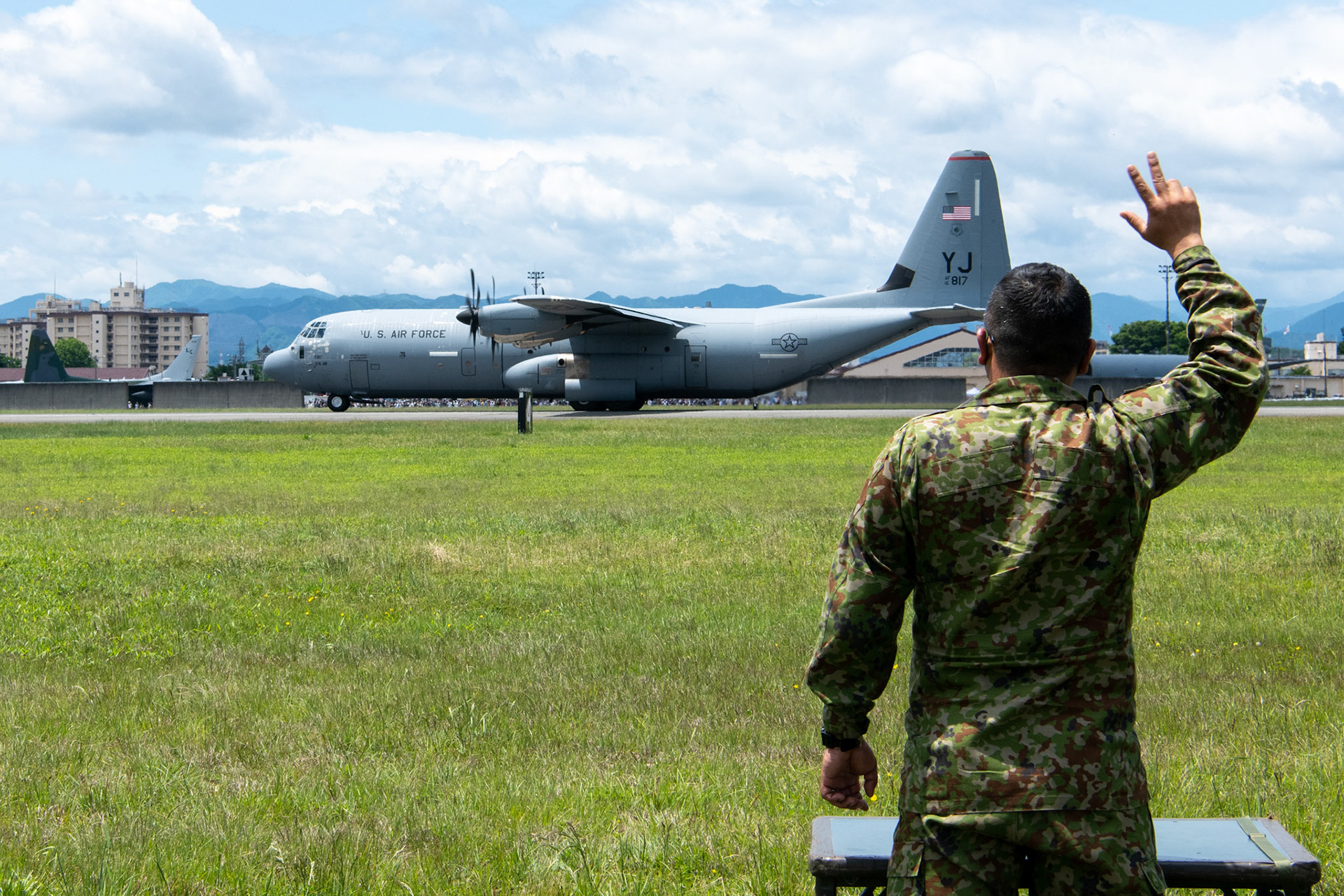 A Japan Ground Self-Defense Force soldier assigned to the 1st Airborne Brigade waves at aircrew of a U.S. Air Force C-130J Super Hercules assigned to 36th Airlift Squadron, as the aircraft takes off during the Japanese-American Friendship Festival at Yokota Air Base, Japan, May 22, 2022. A six member team comprised of U.S. Air Force and JGSDF paratroopers, conducted a military free fall demonstration to show their capabilities during the festival. During the two-day festival, more than 110,000 attendees came to Yokota to experience the event. The festival is aimed at increasing bilateral relationships between U.S. and Japanese communities and allows people to see U.S. and Japanese military capabilities first-hand. (U.S. Air Force photo by Yasuo Osakabe)