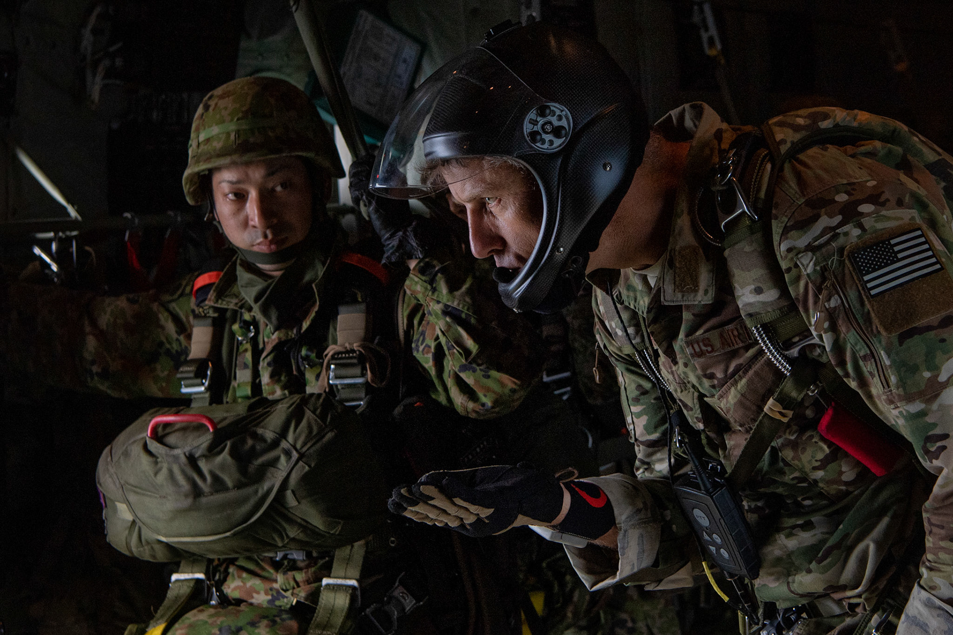 U.S. Air Force Tech Sgt. Seth Sarrett, 374th Operations Support Squadron Survival, Evasion, Resistance and Escape specialist, uses hand signals to communicate with Japan Ground Self-Defense Force paratroopers assigned to the 1st Airborne Brigade as they prepare to exit a U.S. Air Force C-130J Super Hercules from the 36th Airlift Squadron over Hiju-dai exercise area, Oita prefecture, Japan, July 16, 2019, during a bilateral jump training. The training allows USAF and JGSDF units to work alongside each other while improving the readiness of our armed forces. (U.S. Air Force photo by Yasuo Osakabe)