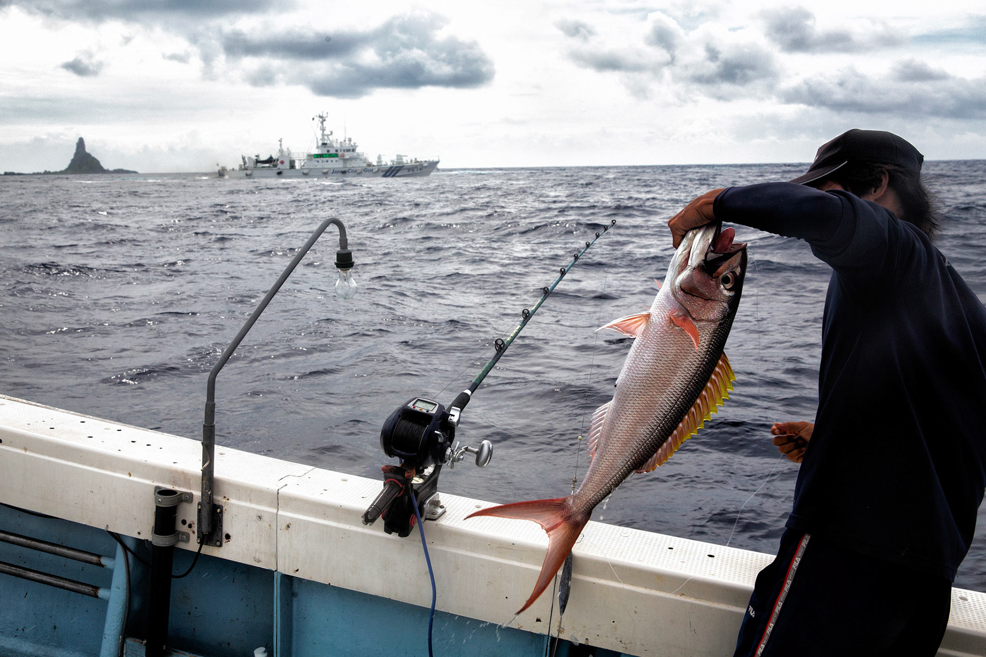 SENKAKU ISLANDS, Japan – A commercial fisherman lands a fish at Minami-kojima, Japan, May 26, 2013. Japanese Coast Guard vessel protected the island and fishermen in case of Chinaese government ships intruding into the territorial waters.  (Photo by Osakabe Yasuo)
