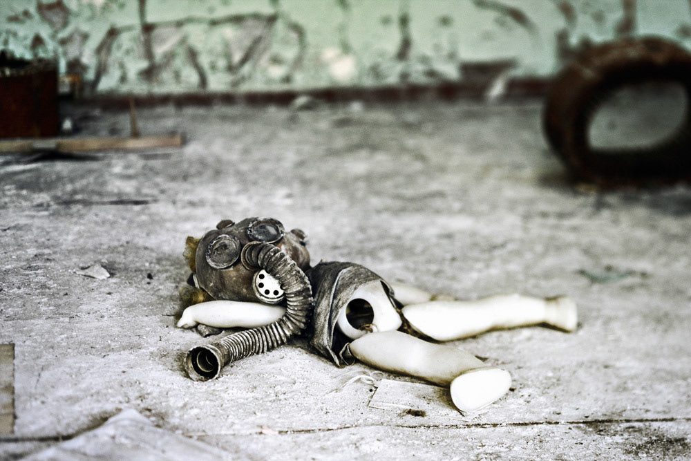 A doll with gas mask lay down on the floor with sadness at a kindergarten, Pripyat.