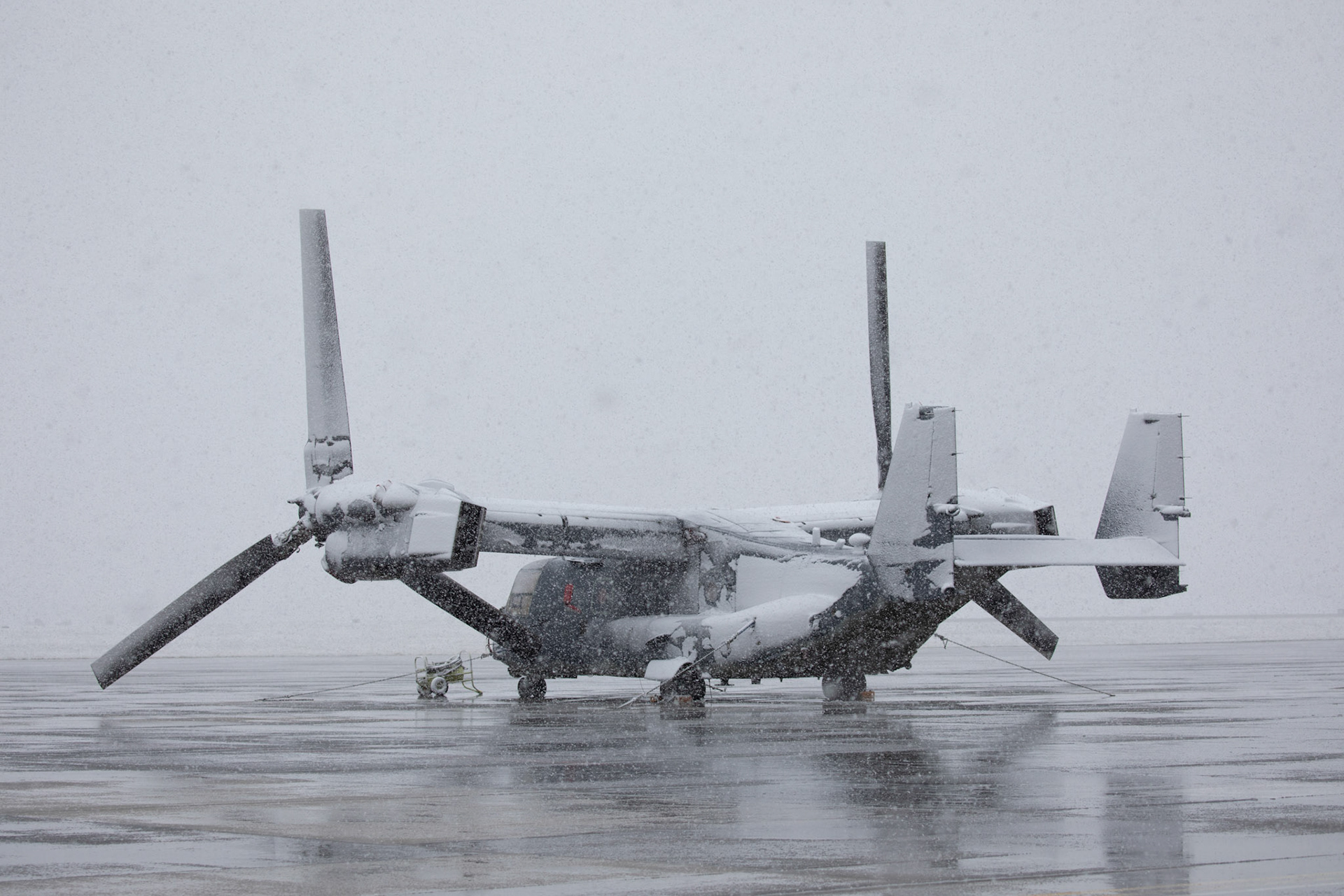 A CV-22 Osprey assigned to the 21st Special Operations Squadron, sits on the flightline during a snow fall March 29, 2020, at Yokota Air Base, Japan. The base recorded more than 2 inches of snowfall during a 12 hour period. This was the fourth morning of the base entering HPCON Charlie in response to the wide-spread novel coronavirus pandemic; Yokota Airmen maintain mission readiness in spite of external challenges. (U.S. Air Force photo by Yasuo Osakabe)