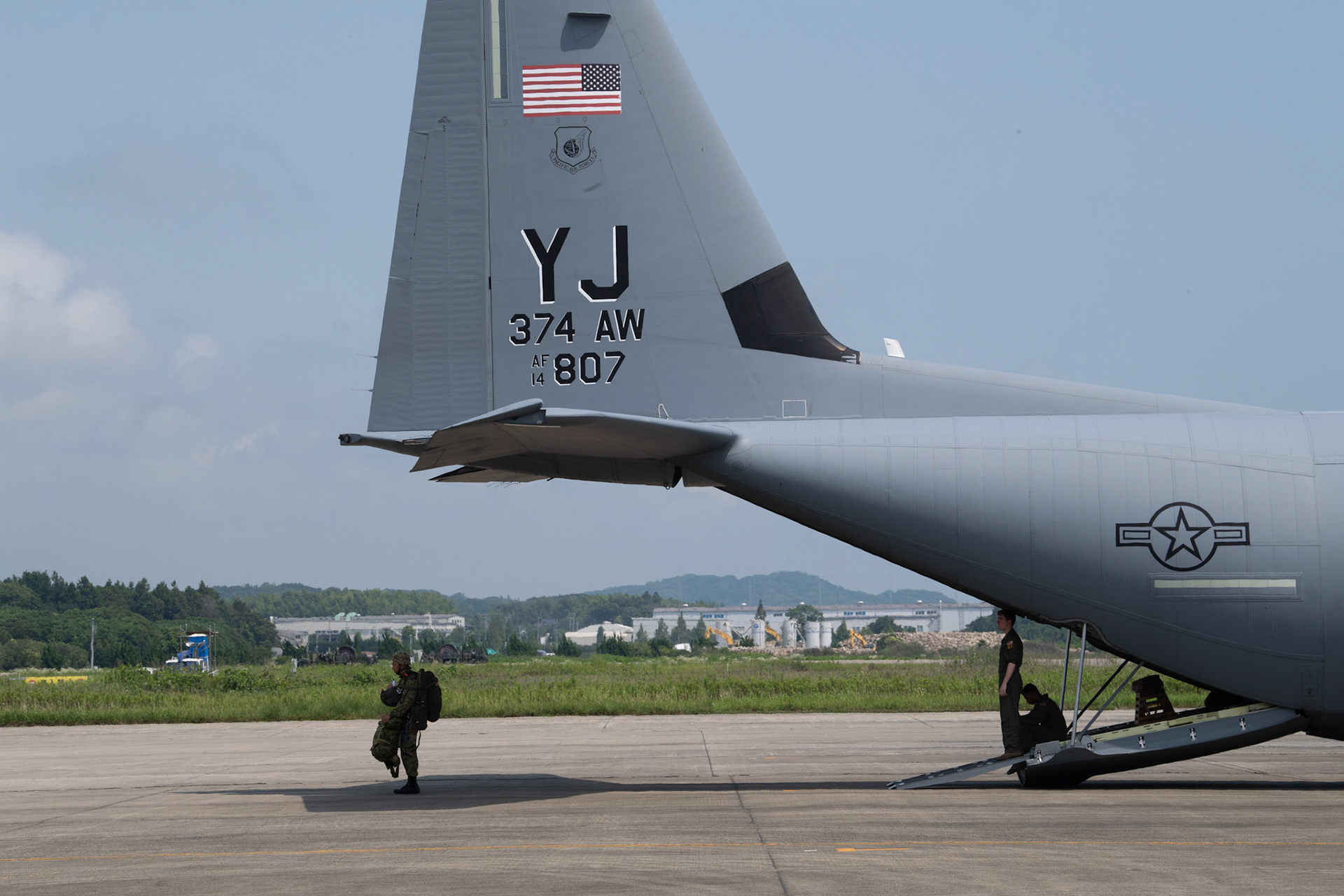 A Japan Ground Self-Defense Force soldier with the 1st Airborne Brigade waits for his troop in front of a U.S. Air Force C-130J Super Hercules assigned to the 36th Airlift Squadron at Japan Air Self-Defense Force Tsuiki Air Base, Japan, July 16, 2019, during a bilateral jump training. The training allows USAF and JGSDF units to work alongside each other while improving the readiness of our armed forces. (U.S. Air Force photo by Yasuo Osakabe)