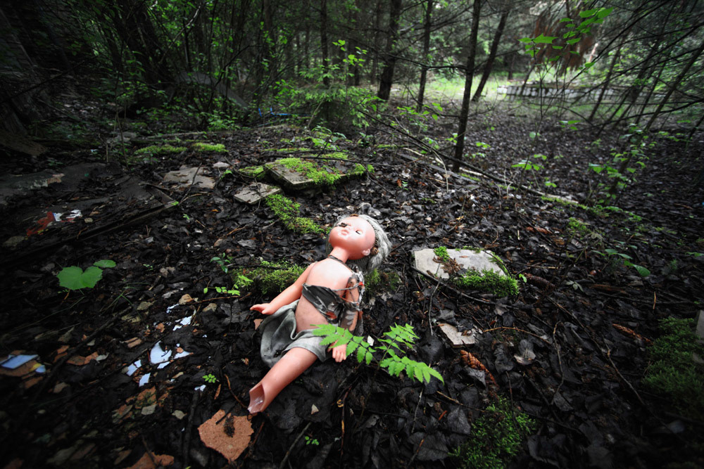 A doll sleeps on her back at the forest by a kindergarten, Pripyat.