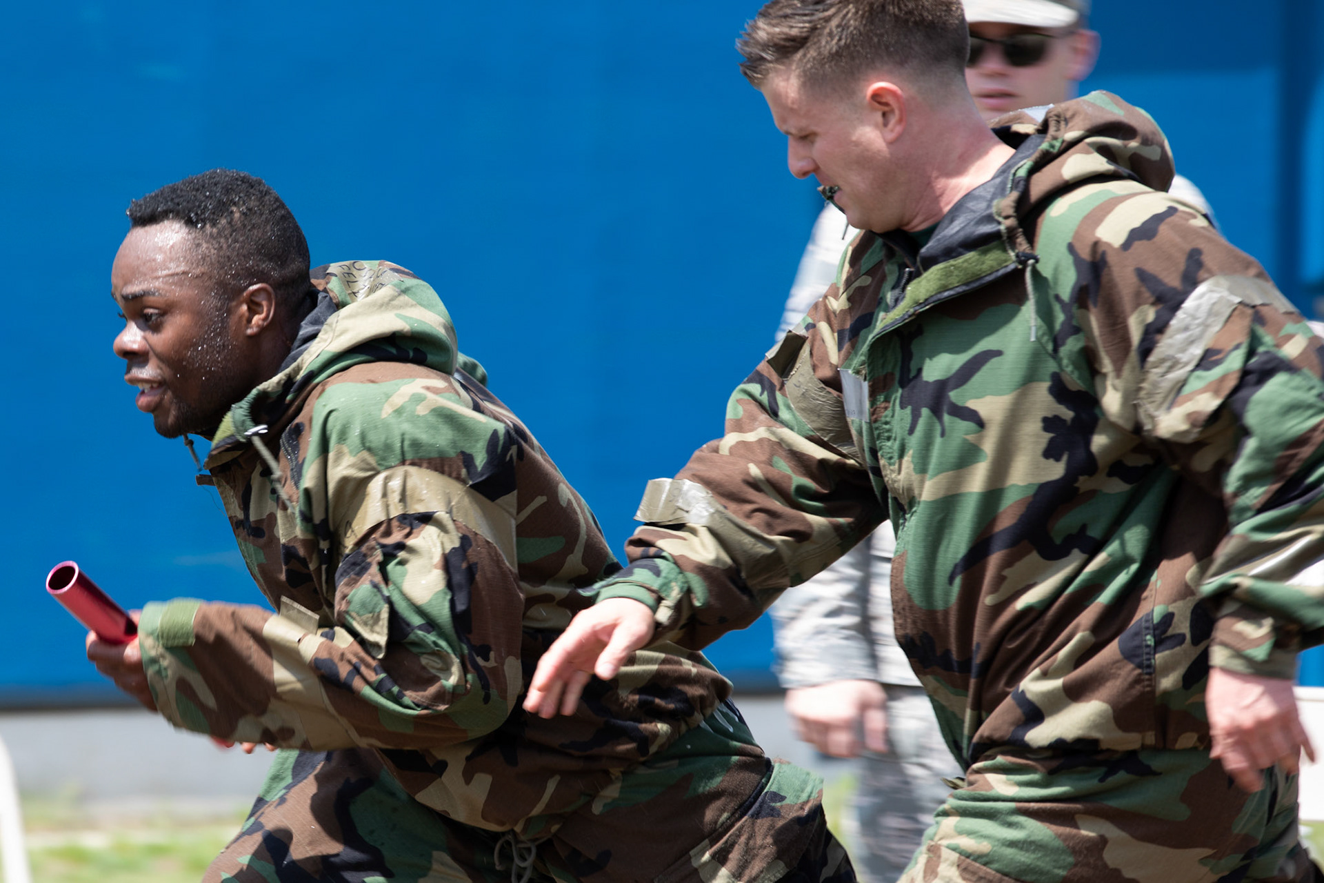 Maj. Logan Smith, 374th Civil Engineer Squadron operations flight commander, passes the baton to Senior Airman Felix Nunez, 374th CES electrical system technician, during an Ability to Survive and Operate (ATSO) Rodeo at Yokota Air Base, Japan, June 8, 2018. The rodeo involved participants wearing different stages of mission-oriented protective posture (MOPP) gear after pushing a Humvee and going through various areas of training including self-aid and buddy care, post-attack reconnaissance, four-person relay, and "shoot, move and communicate." (U.S. Air Force photo by Yasuo Osakabe)