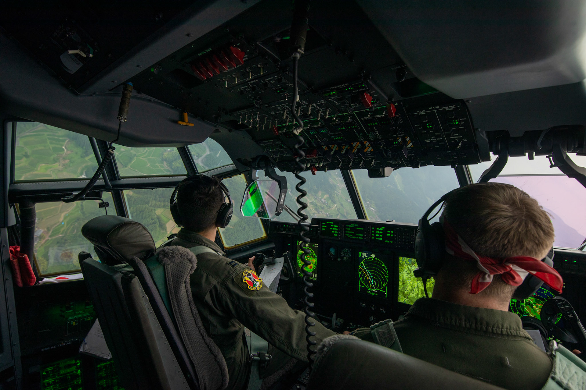 (Left to right) U.S. Air Force Capt. Evan Taylor and Capt. Michael Pyles, 36th Airlift Squadron C-130J pilots, conduct flight training over Mount Aso, Japan, July 16, 2019, during a bilateral jump training. The training allows USAF and JGSDF units to work alongside each other while improving the readiness of our armed forces. (U.S. Air Force photo by Yasuo Osakabe)