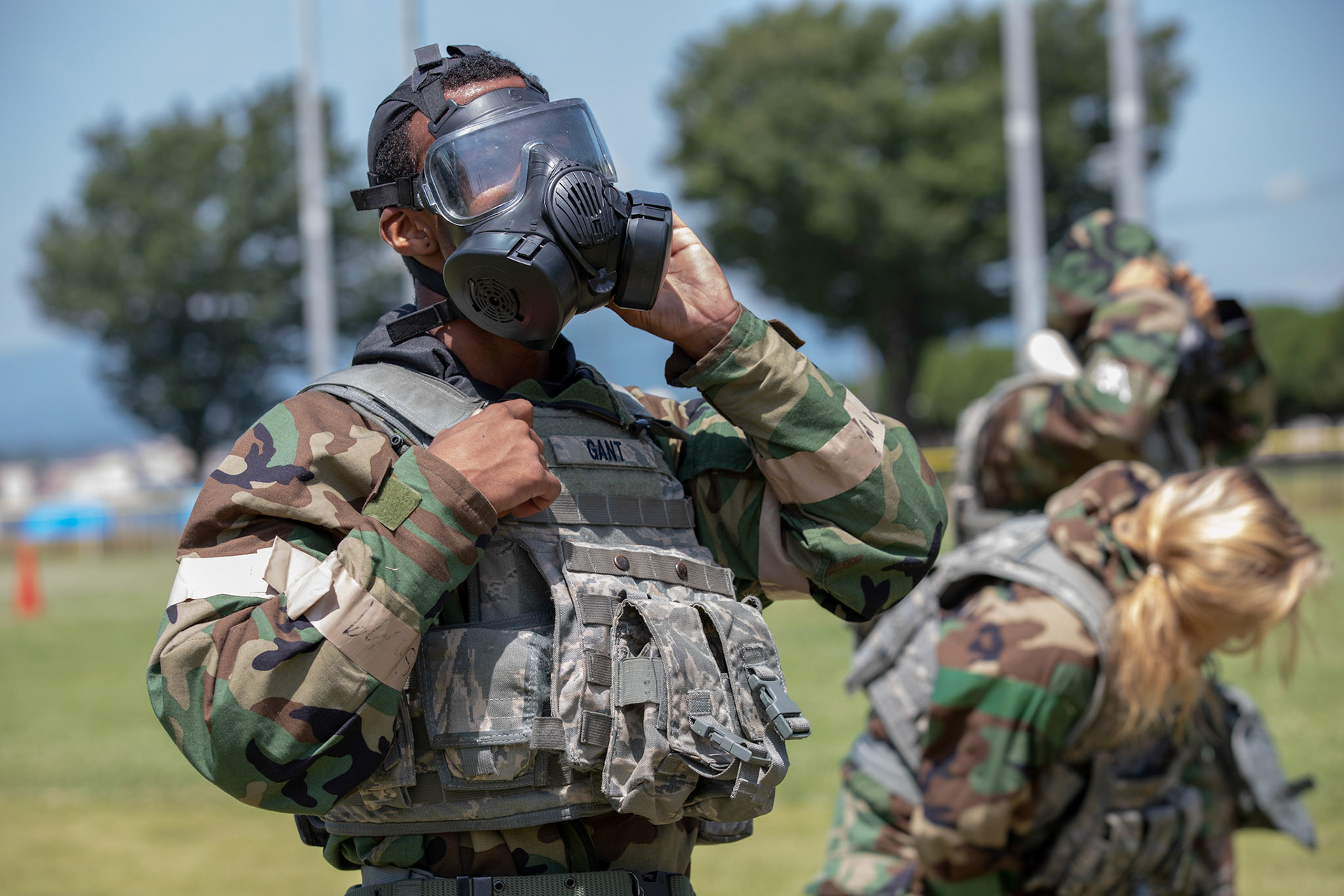 Senior Airman Antonio Gant, left, 374th Security Forces Squadron armorer, dons a mission-oriented protective posture (MOPP) gear during an Ability to Survive and Operate (ATSO) Rodeo at Yokota Air Base, Japan, June 8, 2018. The rodeo involved participants wearing different stages of MOPP gear after pushing a Humvee and going through various areas of training including self-aid and buddy care, post-attack reconnaissance, four-person relay, and "shoot, move and communicate." (U.S. Air Force photo by Yasuo Osakabe)
