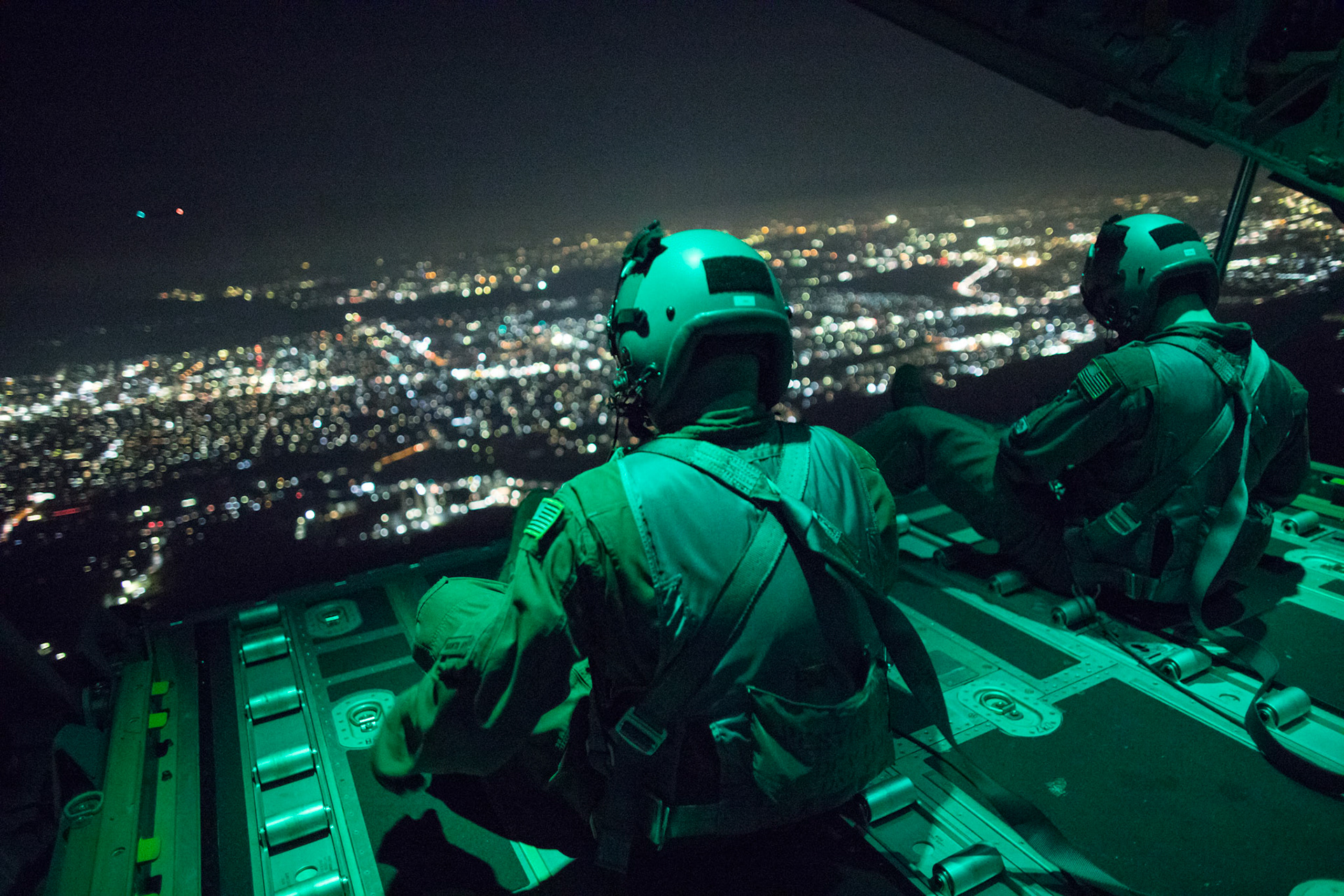 (Left to right) Senior Airman Stephen Clark and Airman 1st Class Matthew Pfeffer, 36th Airlift Squadron C-130J loadmasters, sit on the open ramp of a C-130J Super Hercules flying near Yokota Air Base, Japan, March 26, 2018, before conducting a simulated airdrop over Yokota. Yokota aircrews regularly conduct night flying operations to ensure they are prepared for a variety of contingencies throughout the Indo-Asia Pacific region. (U.S. Air Force photo by Yasuo Osakabe)