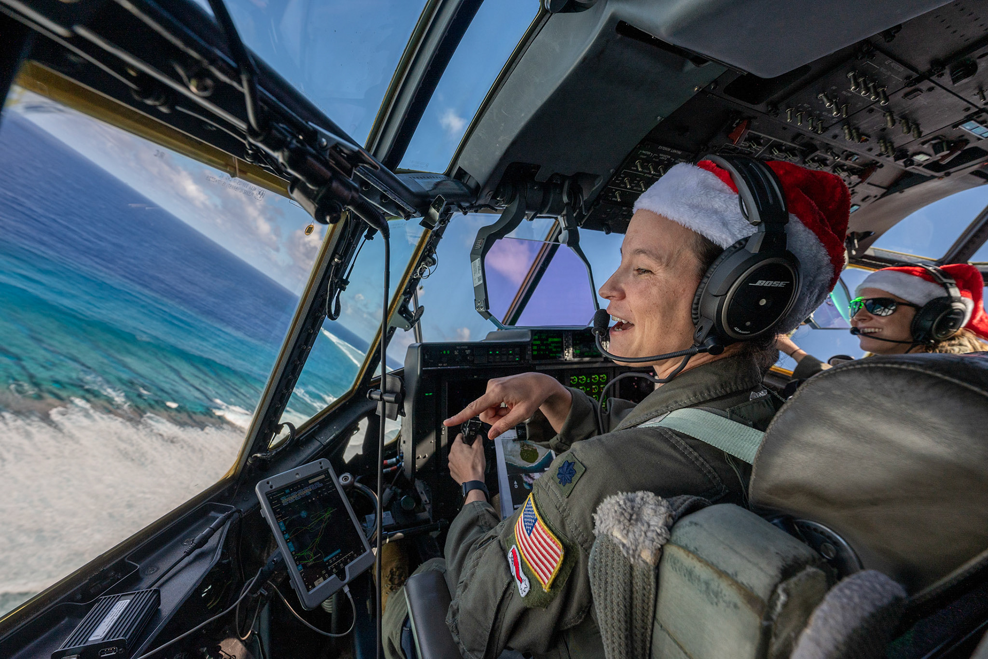 (Left to right) Lt. Col. Kira Coffey, 36th Expeditionary Airlift Squadron commander, and Maj. Chelsie Jones, 36th EAS C-130J pilot, maneuver over Nomwin atoll in the state of Chuuk, Federated States of Micronesia, Dec. 9, 2022, during Operation Christmas Drop 2022. The aircraft, callsign SANTA 67, was the last mission flight of OCD 2022. (U.S. Air Force photo by Yasuo Osakabe)