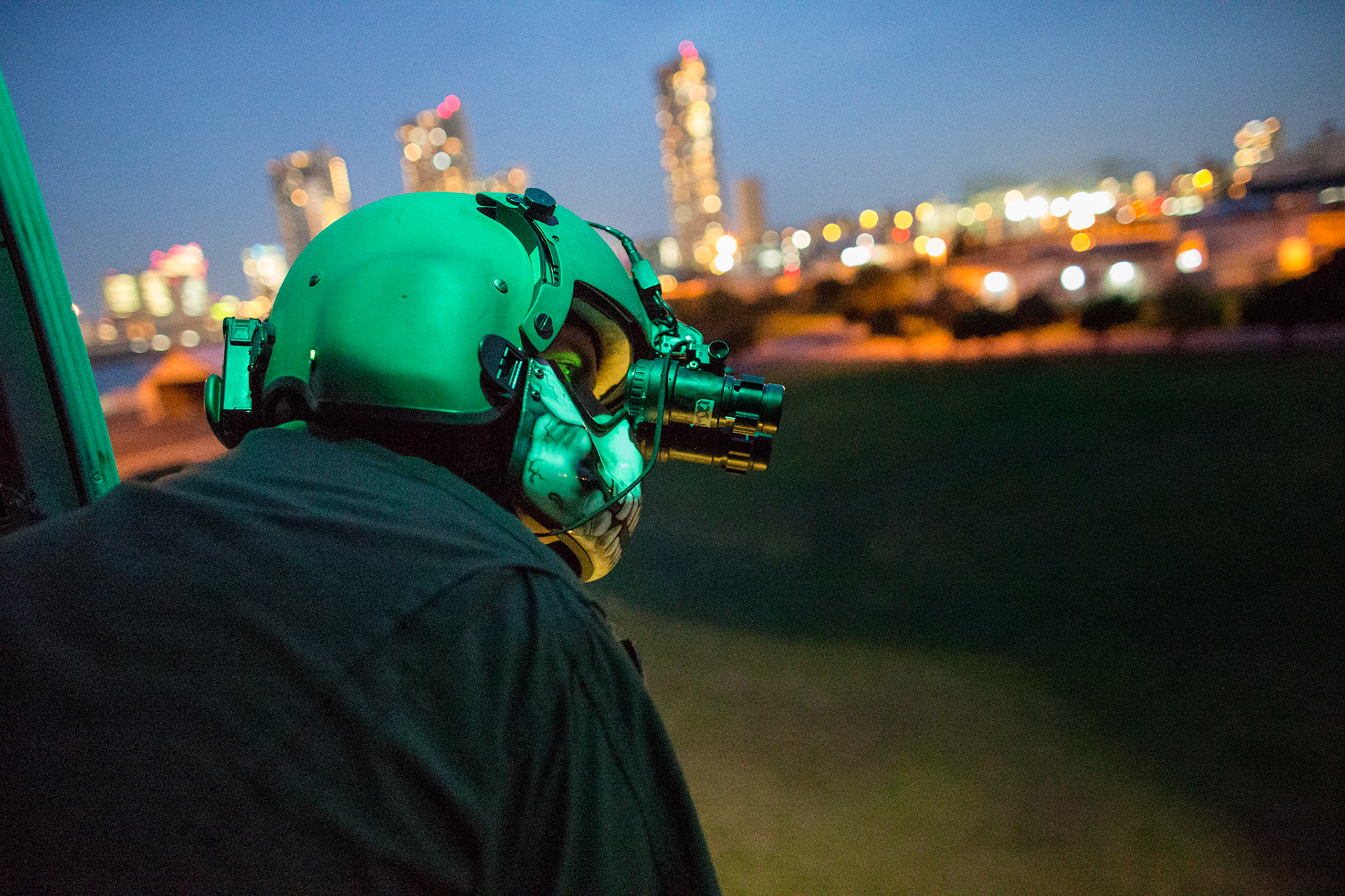 Tech. Sgt. Christopher Rector, 459th Airlift Squadron UH-1N Iroquois special missions aviator evaluator, performs a visual conformation with a night vision goggle during a training flight over U.S. Army Garrison Yokohama North Dock, April 25, 2016. The 459 AS frequently trains on a multitude of scenarios in order to stay prepared for potential real-world contingencies and operations. (U.S. Air Force photo by Yasuo Osakabe/Released)