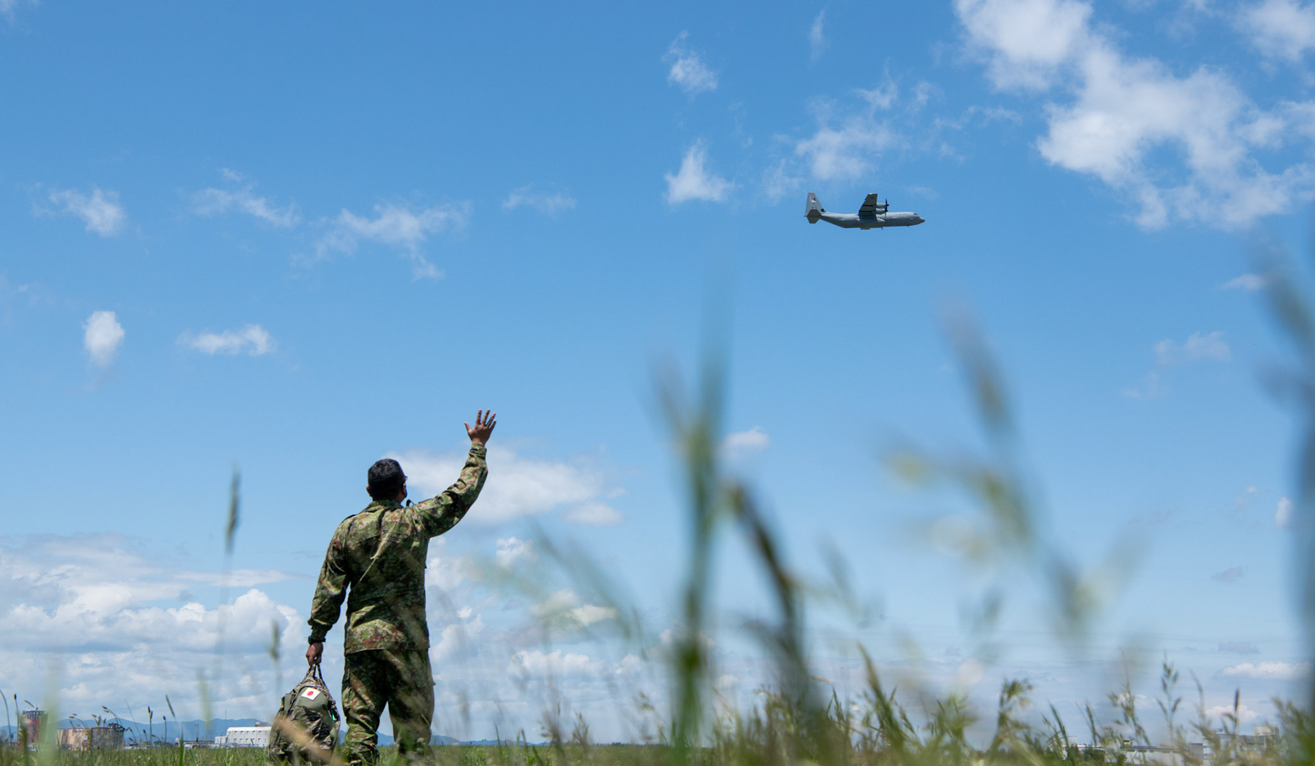 A Japan Ground Self-Defense Force paratrooper assigned to the 1st Airborne Brigade waves to a U.S. Air Force C-130J Super Hercules assigned to the 36th Airlift Squadron during the Japanese-American Friendship Festival at Yokota Air Base, Japan, May 22, 2022. A six member team comprised of U.S. Air Force and JGSDF paratroopers, conducted a military free fall demonstration to show their capabilities during the festival. During the two-day festival, more than 110,000 attendees came to Yokota to experience the event. The festival is aimed at increasing bilateral relationships between U.S. and Japanese communities and allows people to see U.S. and Japanese military capabilities first-hand. (U.S. Air Force photo by Yasuo Osakabe)