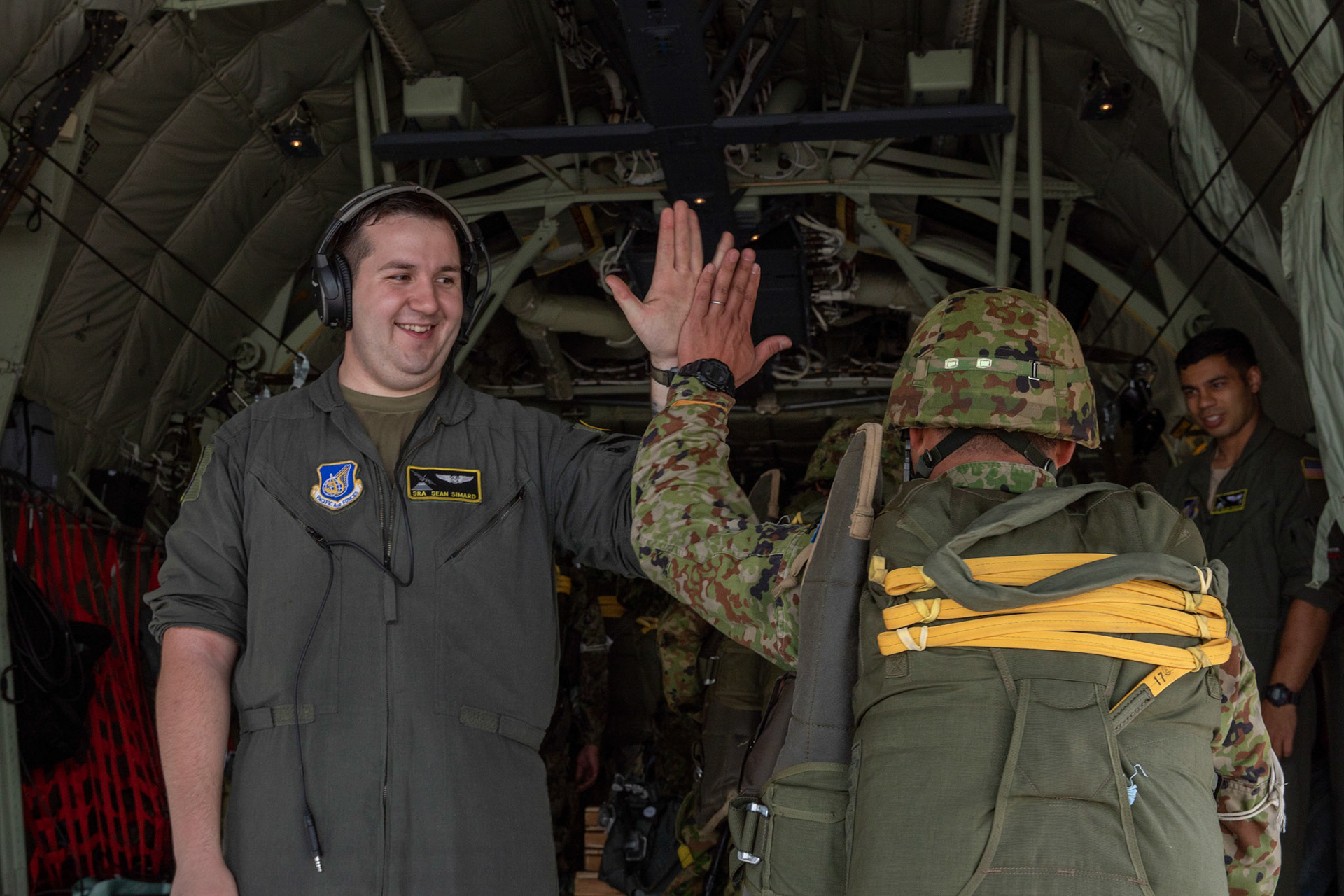 U.S. Air Force Senior Airman Sean Simard, 36th Airlift Squadron loadmaster, high-fives a Japan Ground Self-Defense Force solider assigned to the 1st Airborne Brigade at Japan Air Self-Defense Force Tsuiki Air Base, Japan, July 16, 2019, during a bilateral jump training. The training allows USAF and JGSDF units to work alongside each other while improving the readiness of our armed forces. (U.S. Air Force photo by Yasuo Osakabe)