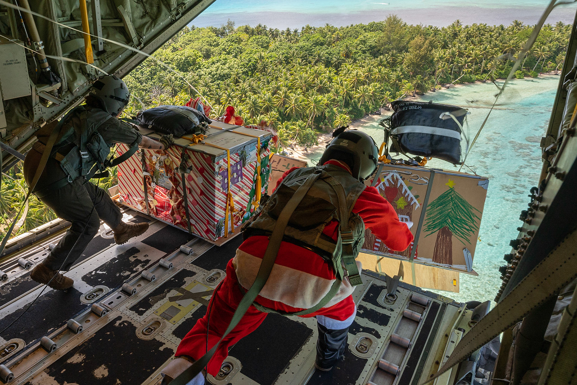 (Left to right) Senior Airman Janealle Hogans, 36th Expeditionary Airlift Squadron loadmaster and Master Sgt. Luke McLimans, 36th EAS operations senior enlisted leader, drop four humanitarian aid bundles over Fananu atoll in the state of Chuuk, Federated States of Micronesia, Dec. 9, 2022, during Operation Christmas Drop 2022. The aircraft, callsign SANTA 67, was the last mission flight of OCD 2022. (U.S. Air Force photo by Yasuo Osakabe)