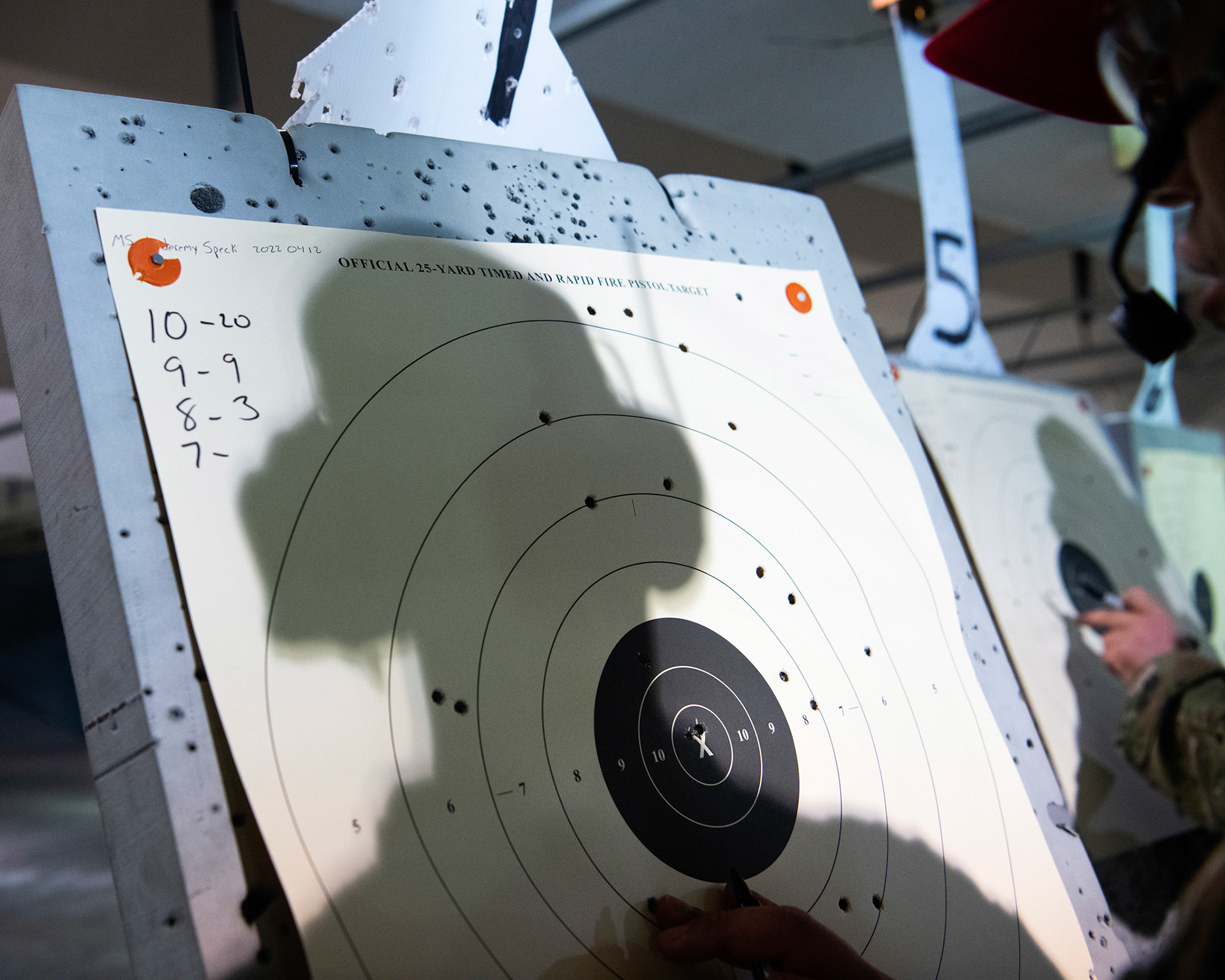 Staff Sgt. Jacque Wilkins, 374th Security Forces Squadron combat arms training and maintenance instructor, scores a target during an Excellence-In-Competition M9 Beretta pistol event at Yokota Air Base, Japan, April 12, 2022. The four-day competition was held to boost morale and test 165 active-duty military members on how accurate they can shoot their authorized duty pistols. The top 10% scorers will earn the Air Force Excellence In Competition medal to wear on the Service Dress Uniform. (U.S. Air Force photo by Yasuo Osakabe)