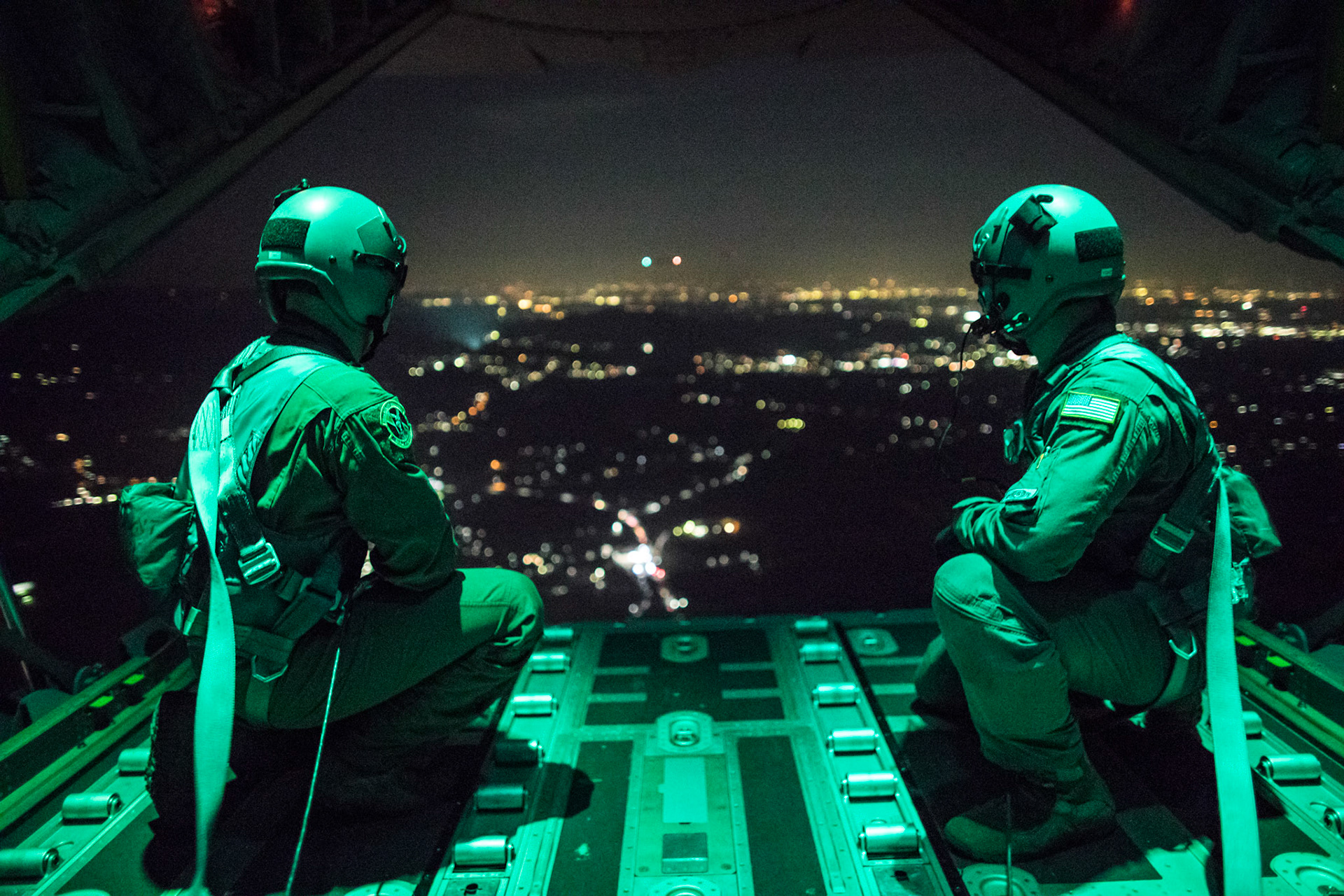(Left to right) Senior Airman Stephen Clark and Airman 1st Class Matthew Pfeffer, 36th Airlift Squadron C-130J loadmasters, sit on the open ramp of a C-130J Super Hercules flying near Yokota Air Base, Japan, March 26, 2018, before conducting a simulated airdrop over Yokota. Yokota aircrews regularly conduct night flying operations to ensure they are prepared for a variety of contingencies throughout the Indo-Asia Pacific region. (U.S. Air Force photo by Yasuo Osakabe)