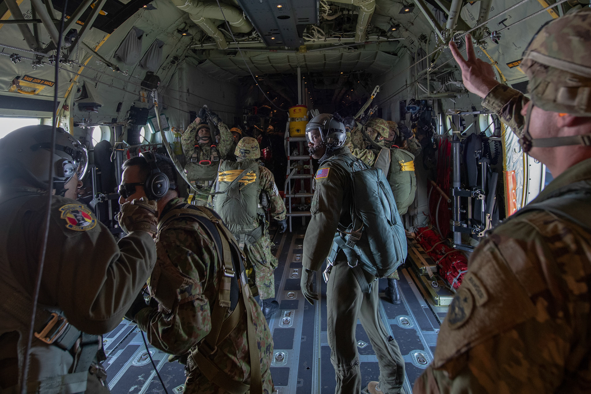 U.S. Army Master Sgt. Nathan Greer, right, U.S. Army Alaska jump master, gives a hand signal to Japan Ground Self-Defense Force soldiers assigned to the 1st Airborne Brigade over Hiju-dai drop zone, Oita prefecture, Japan, Nov. 4, 2018, during Keen Sword 19. Approximately 280 JGSDF personnel conducted jump training from U.S. Air Force C-130J Super Hercules’ for the first time in Japan. (U.S. Air Force photo by Yasuo Osakabe)