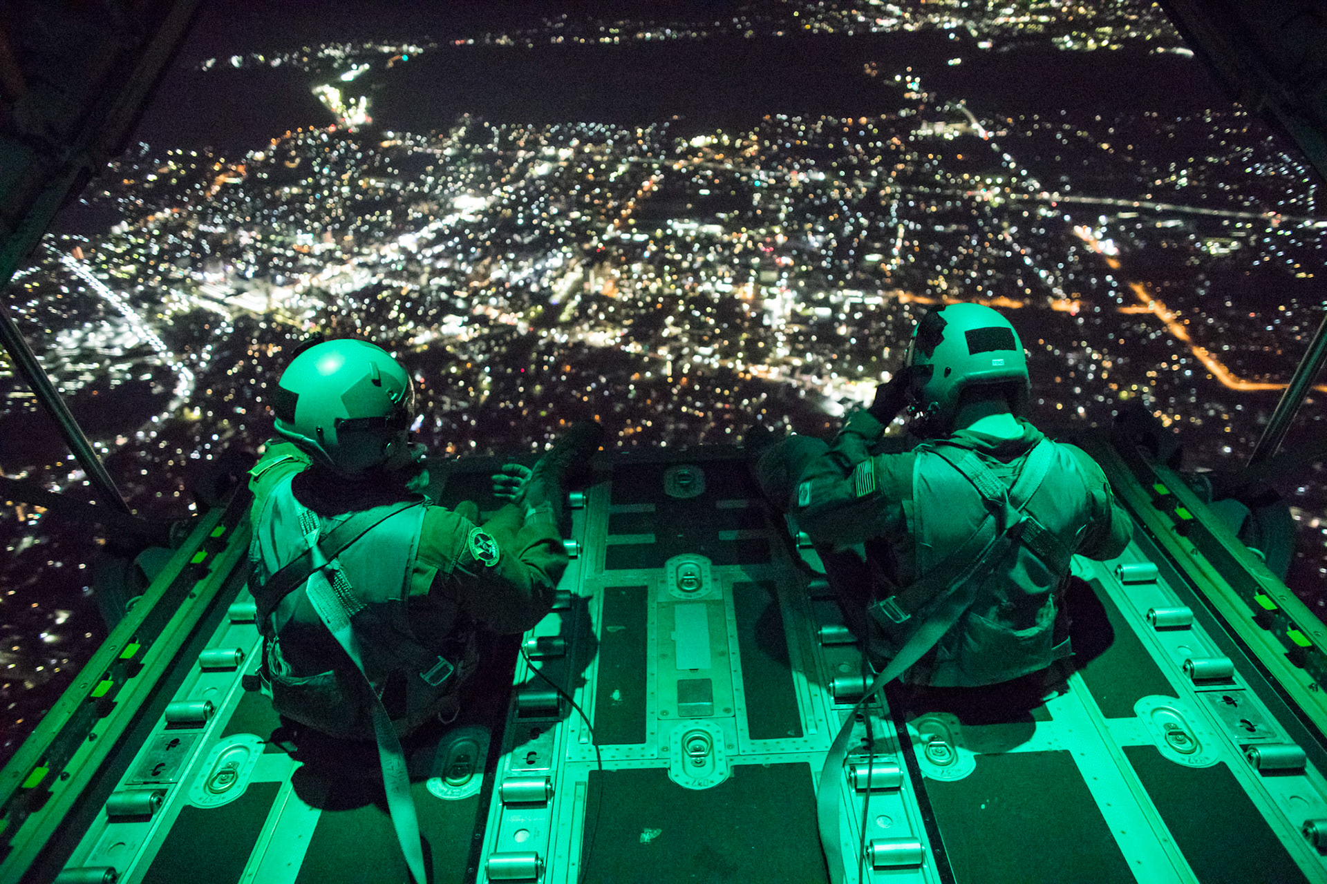 (Left to right) Senior Airman Stephen Clark and Airman 1st Class Matthew Pfeffer, 36th Airlift Squadron C-130J loadmasters, sit on the open ramp of a C-130J Super Hercules flying near Yokota Air Base, Japan, March 26, 2018, before conducting a simulated airdrop over Yokota. Yokota aircrews regularly conduct night flying operations to ensure they are prepared for a variety of contingencies throughout the Indo-Asia Pacific region. (U.S. Air Force photo by Yasuo Osakabe)