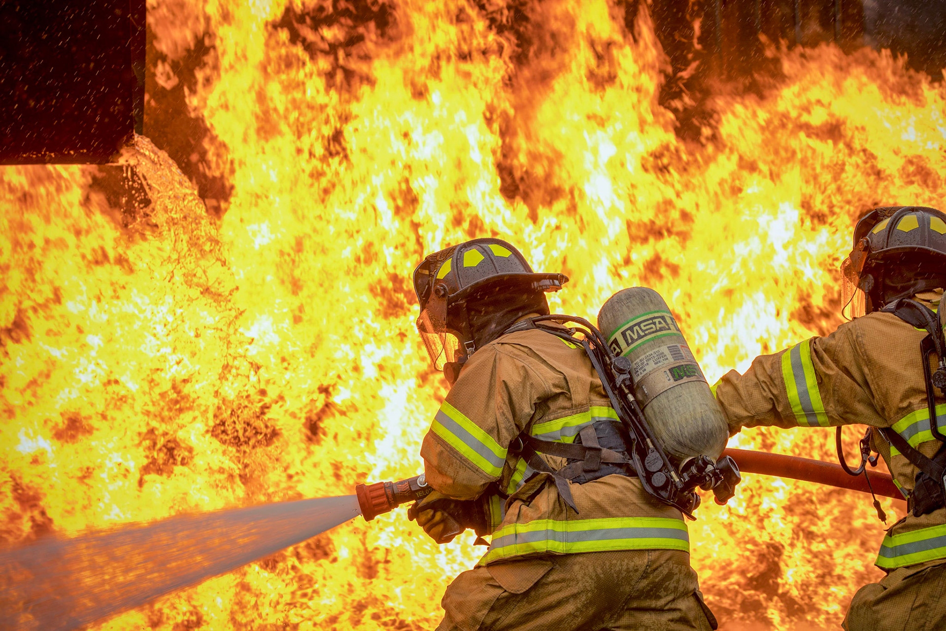 A two-person fire attack crew with the 374th Civil Engineer Squadron fire and emergency services flight aim a stream of water on a simulated aircraft fire at Yokota Air Base, Japan, March 8, 2018. Aircraft live-fire training is conducted periodically throughout the year to ensure Airmen and civilians with the 374th CES and 374th Maintenance Squadron repair and reclamation section are always prepared to combat aircraft fuel fires. (U.S. Air Force photo by Yasuo Osakabe)