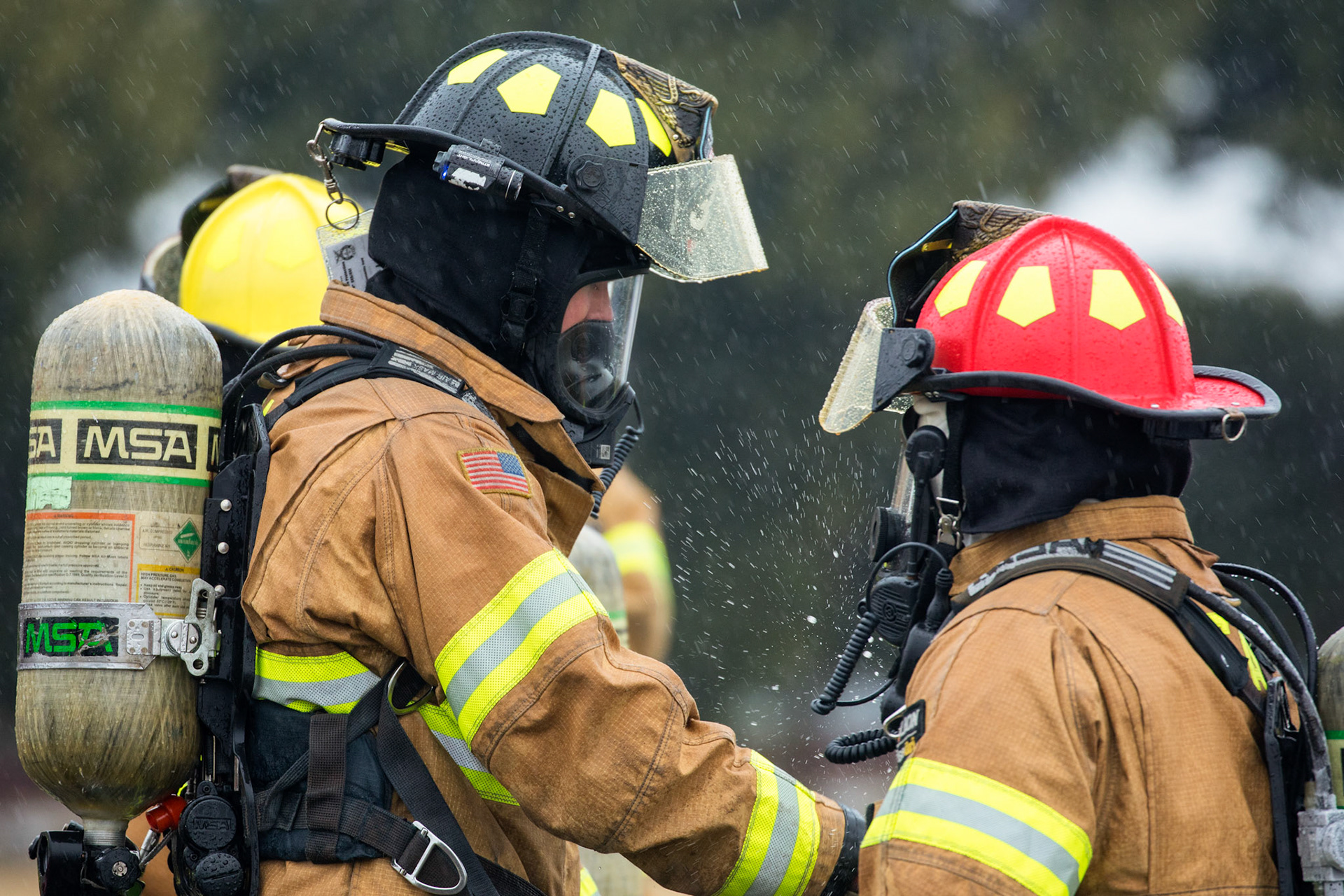 Senior Airman Thomas Smith, left, 374th Civil Engineer Squadron firefighter, fastens and checks  protective gear for Hidekazu Suzuki, 374th CES firefighter, while conducting simulated aircraft fire drills at Yokota Air Base, Japan, March 8, 2018. Aircraft live-fire training is conducted periodically throughout the year to ensure Airmen and civilian firefighters with the Yokota Fire Department and 374th Maintenance Squadron repair and reclamation section are always prepared to combat aircraft fuel fire. (U.S. Air Force photo by Yasuo Osakabe)