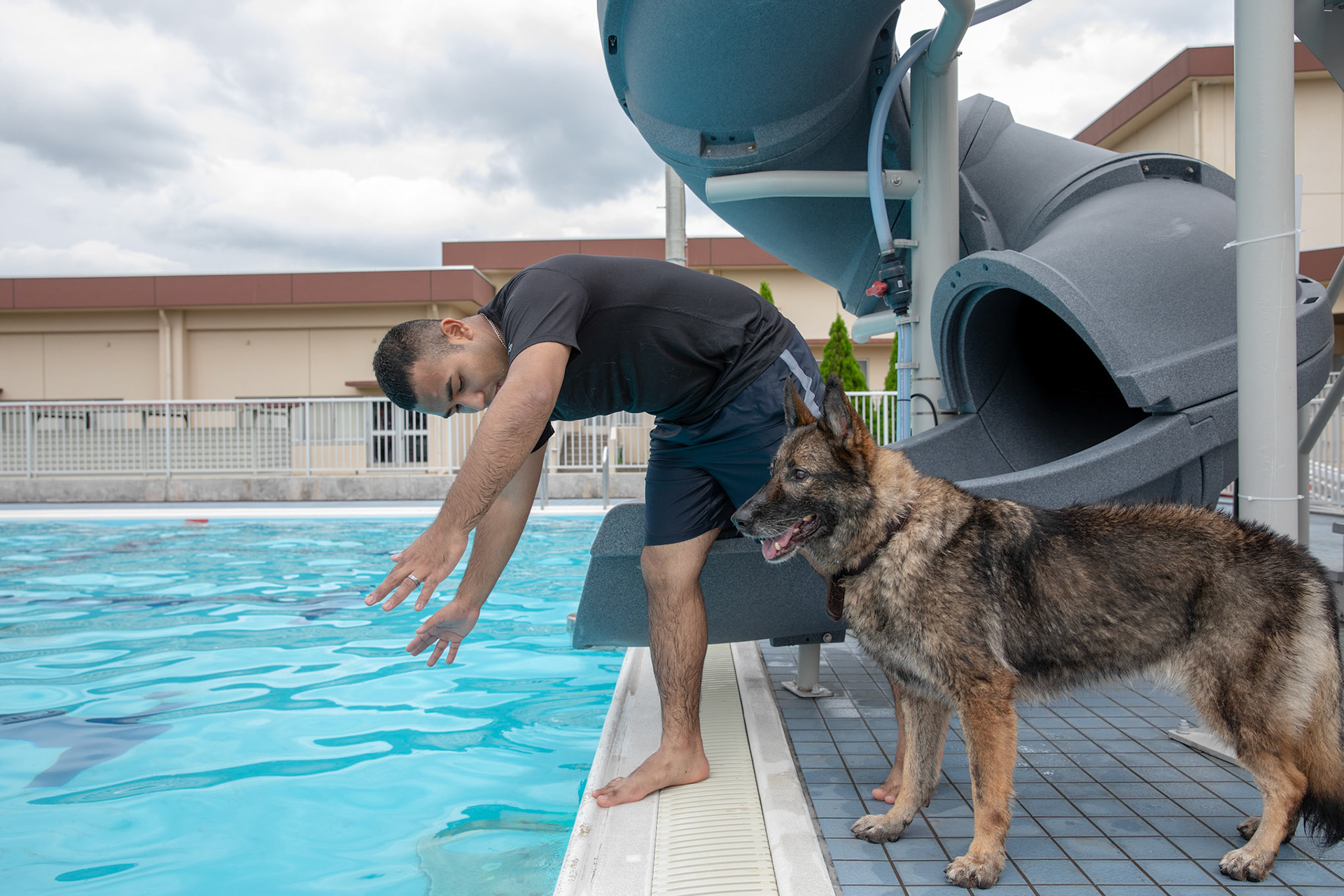 Staff Sgt. Mario Hernandez, 374th Security Forces Squadron military working dog handler, tells Demo, 374th SFS military working dog, to leap from the edge of a pool during a water-based aggression training at Yokota Air Base, Japan, Sept. 12, 2018. MWDs performed bite drills designed to slow down or stop suspects attempting to flee apprehension by escaping into a body of water. (U.S. Air Force photo by Yasuo Osakabe)