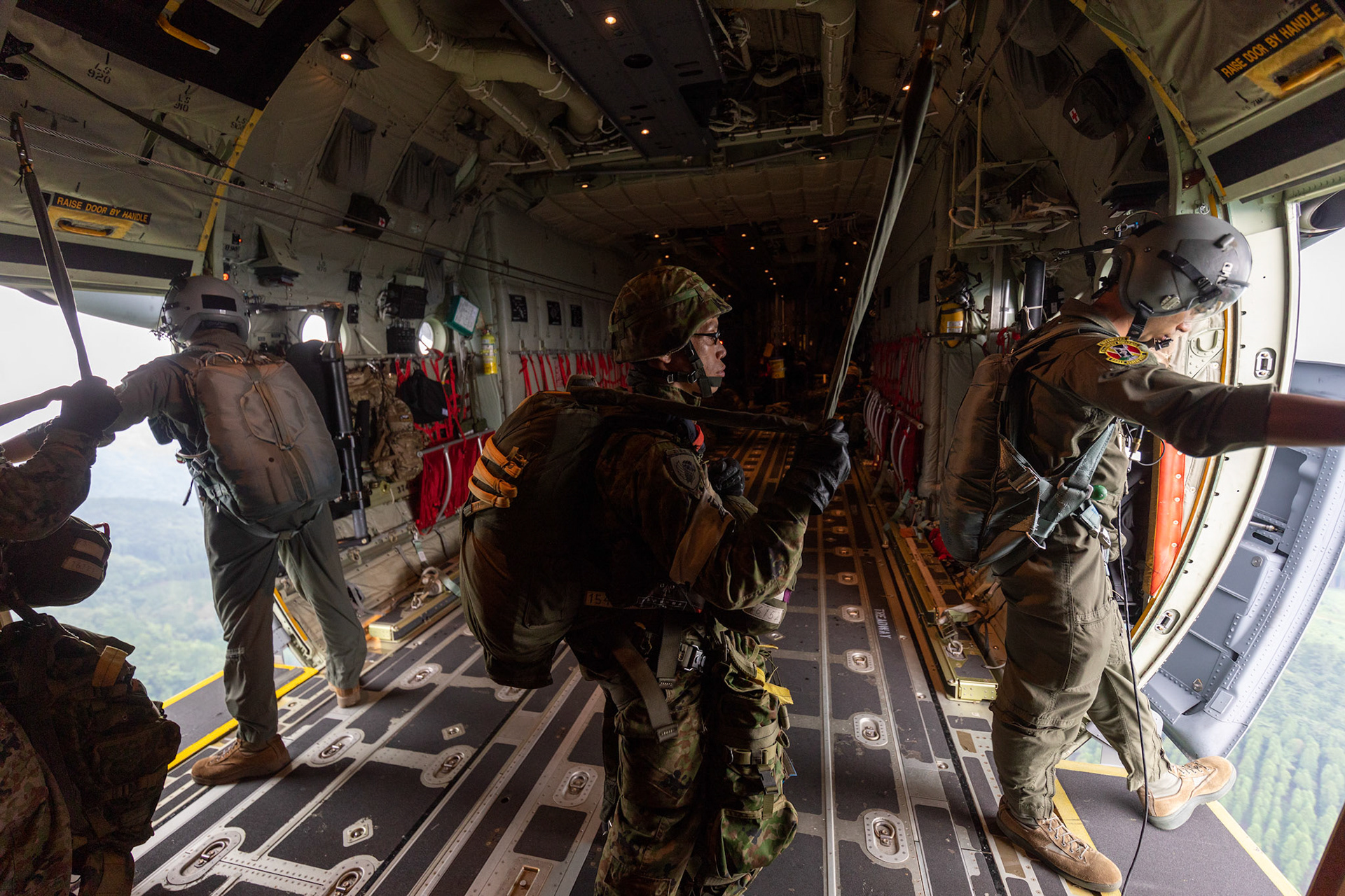 (Right to left) U.S. Air Force Staff Sgt. Water Frank and Senior Airman Jaime Suarez, 36th Airlift Squadron loadmasters, perform visual confirmations after Japan Ground Self-Defense Force paratroopers assigned to the 1st Airborne Brigade jump from a U.S. Air Force C-130J Super Hercules over Hiju-dai exercise area, Oita prefecture, Japan, July 16, 2019, during a bilateral jump training. The training allows USAF and JGSDF units to work alongside each other while improving the readiness of our armed forces. (U.S. Air Force photo by Yasuo Osakabe)