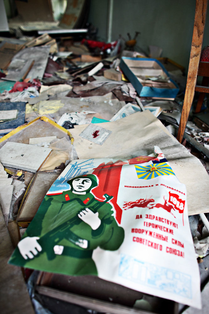 a Soviet propaganda poster is scatters on a floor at a school, Pripyat.