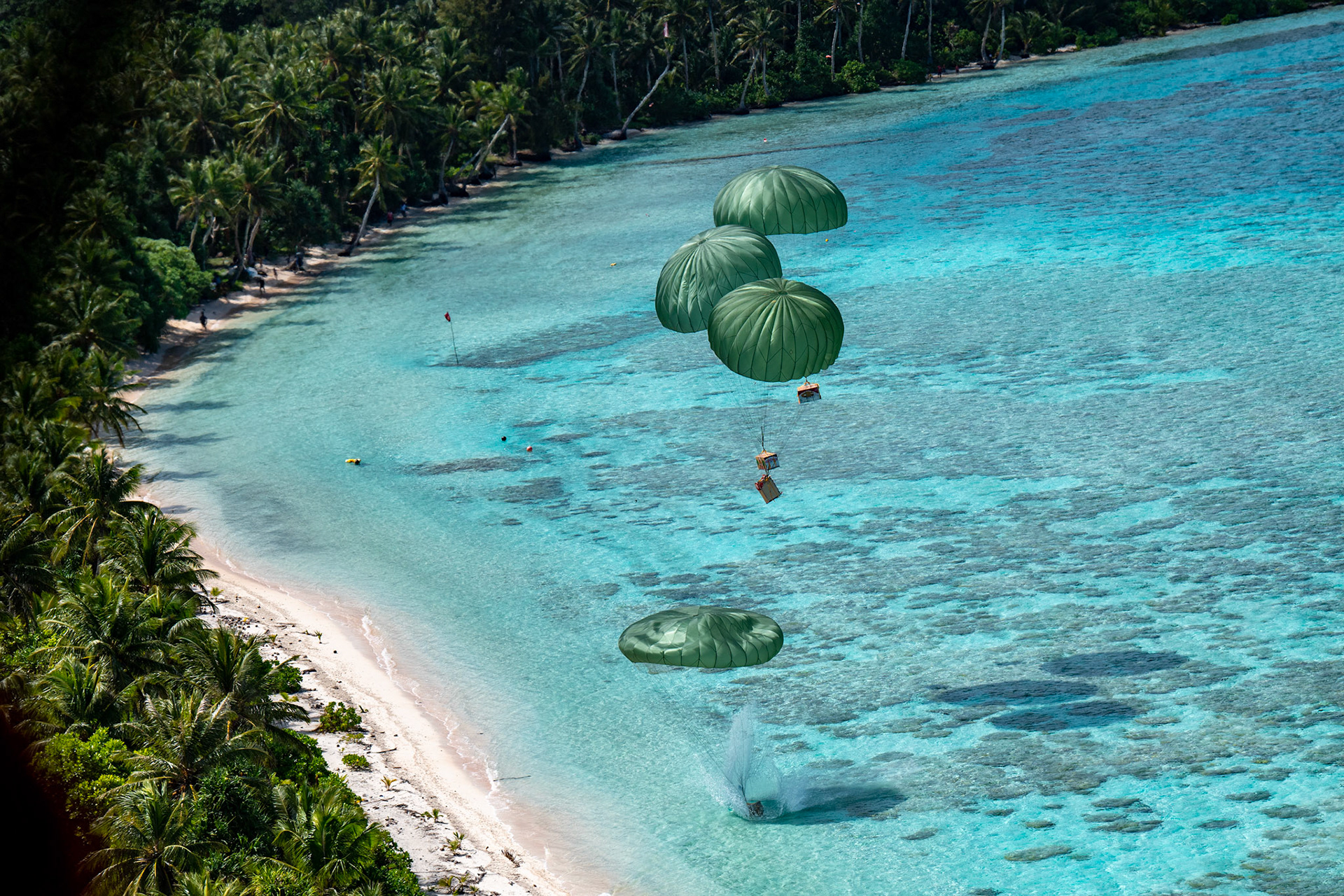 Four humanitarian aid bundles descend from a U.S. Air Force C-130J Super Hercules assigned to the 36th Expeditionary Airlift Squadron over Fananu atoll in the state of Chuuk, Federated States of Micronesia, Dec. 9, 2022, during Operation Christmas Drop 2022. The aircraft, callsign SANTA 67, was the last mission flight of OCD 2022. following a mission during OCD 2015. (U.S. Air Force photo by Yasuo Osakabe)
