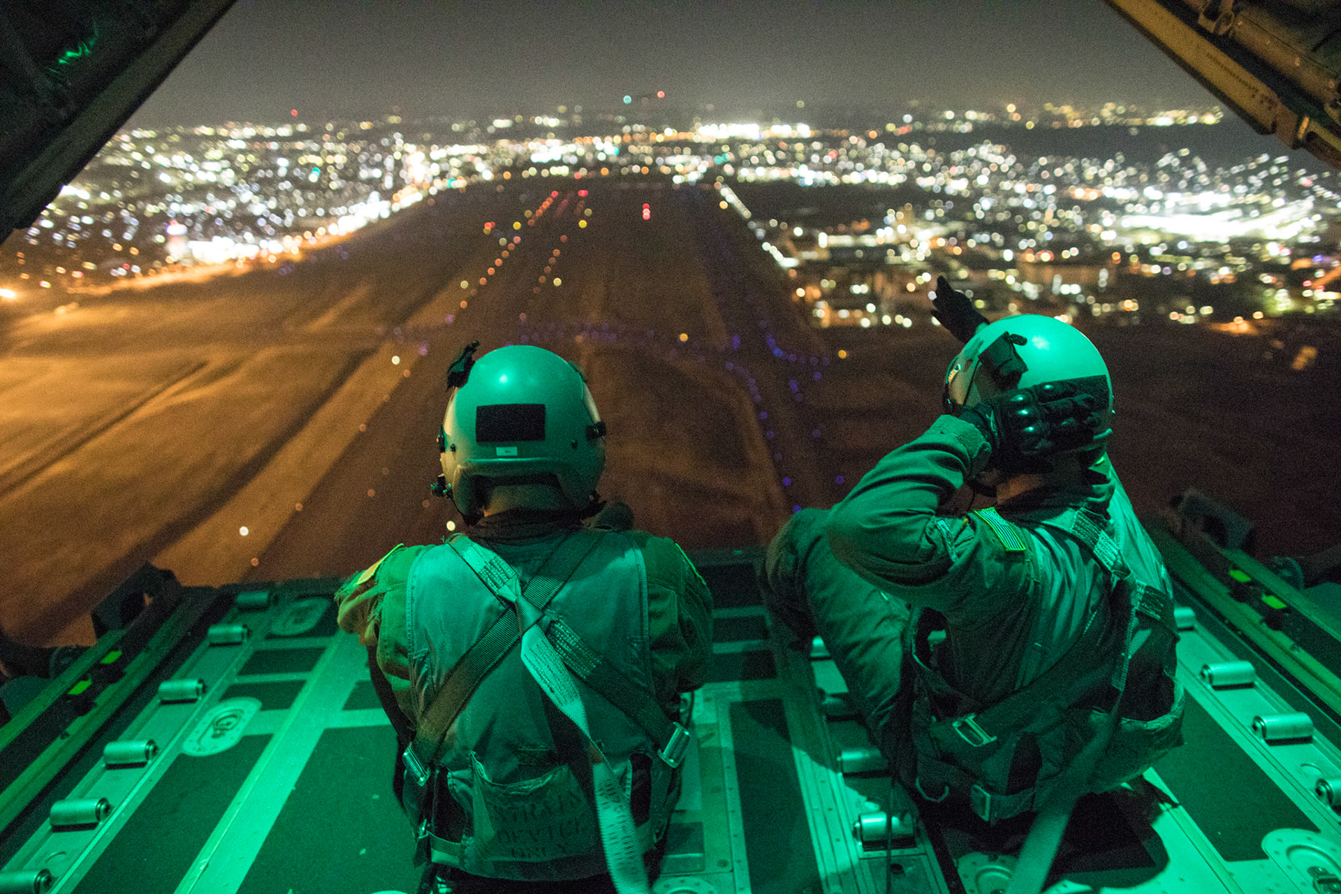 (Left to right) Senior Airman Stephen Clark and Airman 1st Class Matthew Pfeffer, 36th Airlift Squadron C-130J loadmaster, perform a simulated airdrop over Yokota Air Base, Japan, March 26, 2018. Yokota aircrews regularly conduct night flying operations to ensure they are prepared for a variety of contingencies throughout the Indo-Asia Pacific region. (U.S. Air Force photo by Yasuo Osakabe)