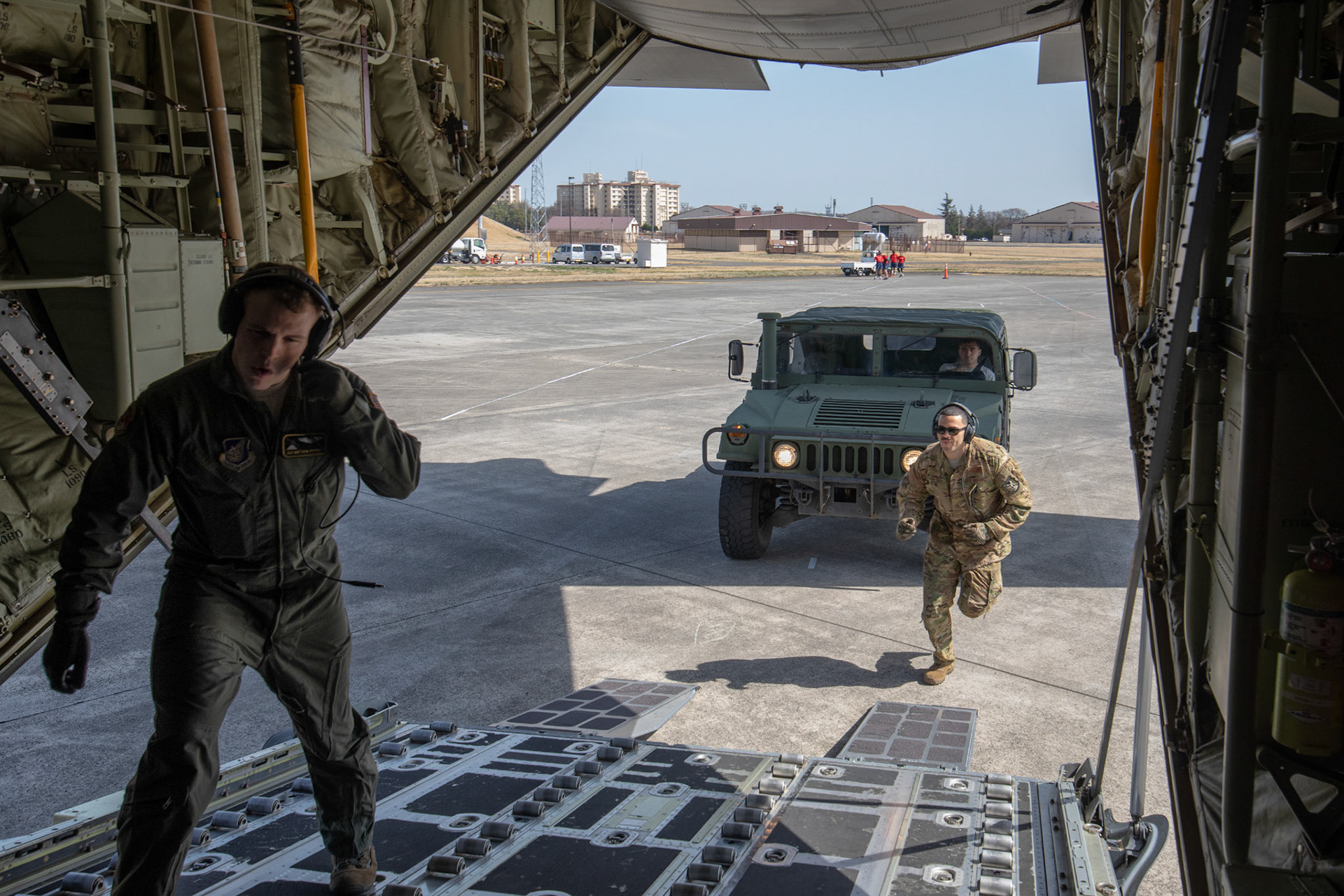 (Left to right) Airman 1st Class Matthew Pfeffer and Tech. Sgt. Brian Gates, both with the 36th Airlift Squadron C-130J loadmasters, help guide the driver of a Humvee vehicle onto a C-130J Super Hercules during the Yokota C-130J Rodeo at Yokota Air Base, Japan, March 22, 2018. Throughout the Yokota C-130J Rodeo competition, each team was faced with a series of tactical events such as combat on and off-loading, airdrops and assault landings. (U.S. Air Force photo by Yasuo Osakabe)