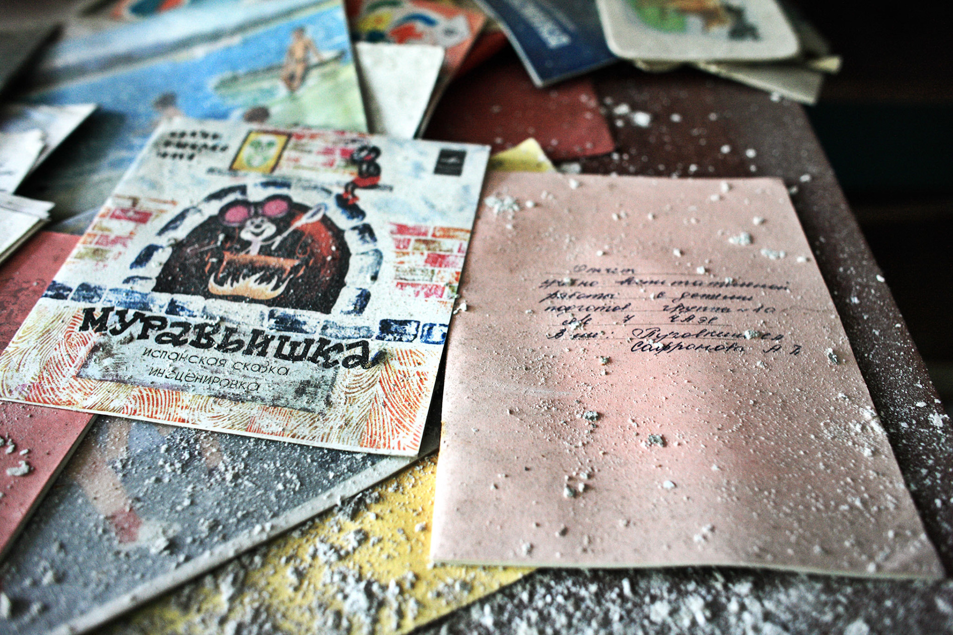 A document and picture with a dusts mess up on a table at a kindergarten, Pripyat.