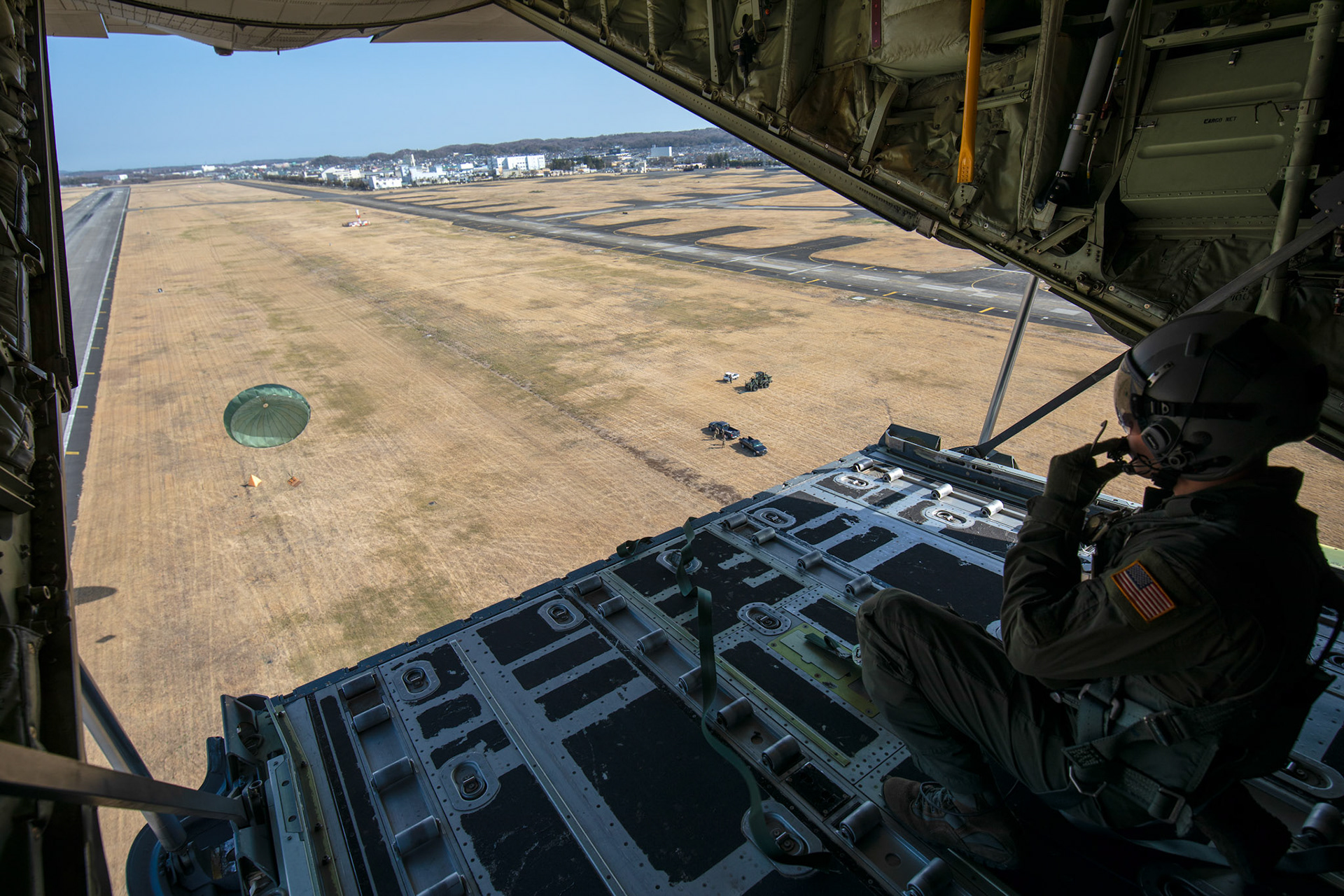 Airman 1st Class Matthew Pfeffer, 36th Airlift Squadron C-130J loadmaster, communicates with crewmembers after conducting a low-cost low-altitude bundle airdrop during the Yokota C-130J Rodeo over Yokota Air Base, Japan, March 22, 2019. The flight, airdrop, and offload were a part of the Rodeo competition, in which pilots and loadmasters are graded on their ability to execute their skillsets both accurately and expeditiously. (U.S. Air Force photo by Yasuo Osakabe)