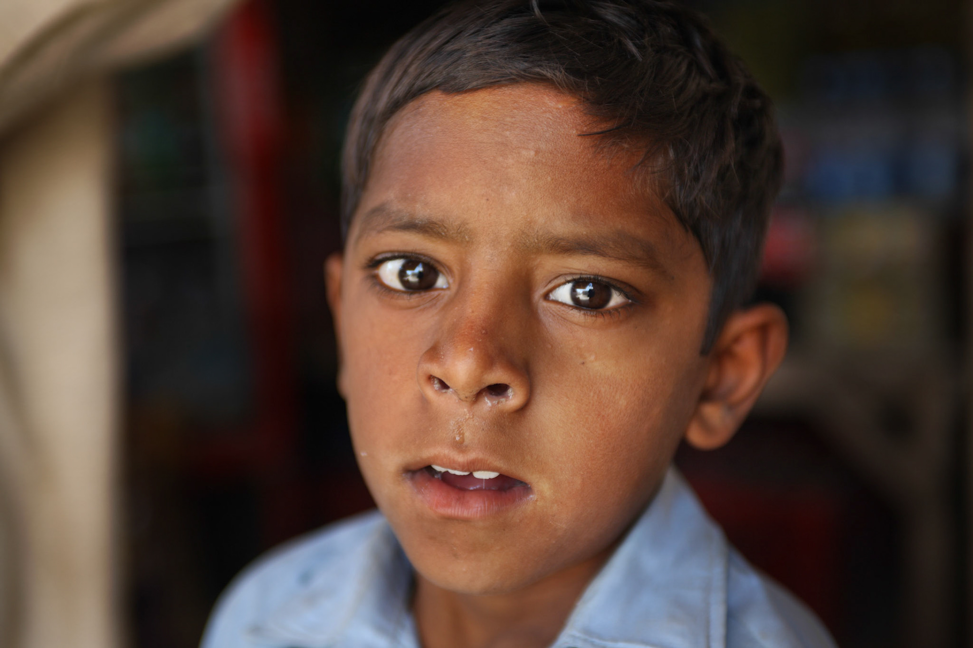 A quiet boy just sit down the glossary shop with his father for looking after shop. (Travel)