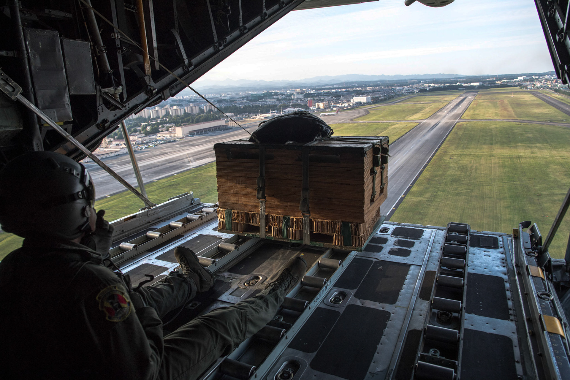 Senior Airman Gary Coe, 36th Airlift Squadron C-130H loadmaster, drops a low-cost, low-altitude bundle over Yokota Air Base, Japan, Oct. 5, 2017. This is the last time active duty C-130H Hercules' crew members perform an LCLA airdrop. (U.S. Air Force photo by Yasuo Osakabe)