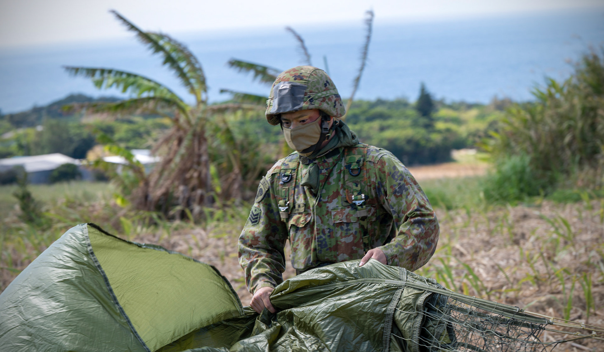A Japan Ground Self-Defense Force paratrooper assigned to the 1st Airborne Brigade packs his parachute after completing a static-line jump during Field Training Exercise Iron Fist 23 at Kikaijima Island, Japan, March 3, 2023. During the exercise, the USAF and Japan Self-Defense Forces conducted simulated island seizure airborne operations as the U.S. Marine Corps performed a simultaneous amphibious assault onto the beachhead. (U.S. Air Force photo by Yasuo Osakabe)